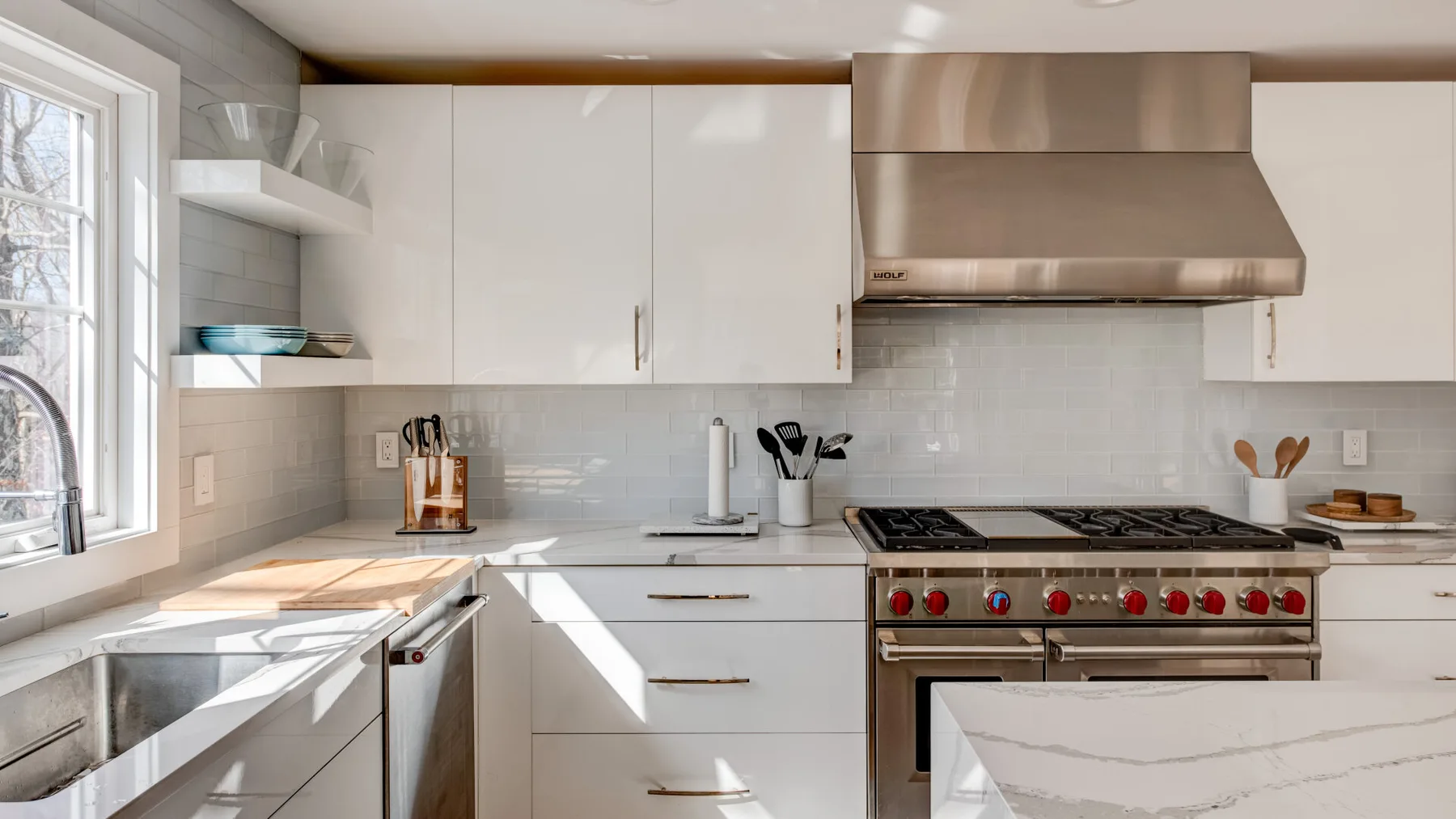 Una cocina luminosa con gabinetes blancos, una estufa grande y una ventana sobre el fregadero.