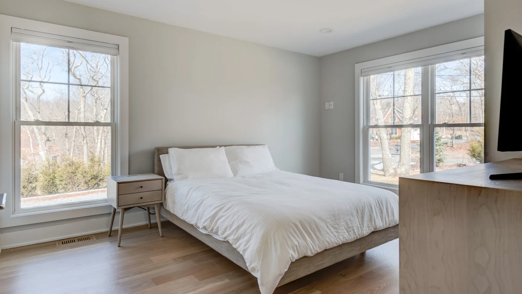 Un dormitorio con una cama, una mesita de noche y grandes ventanas.