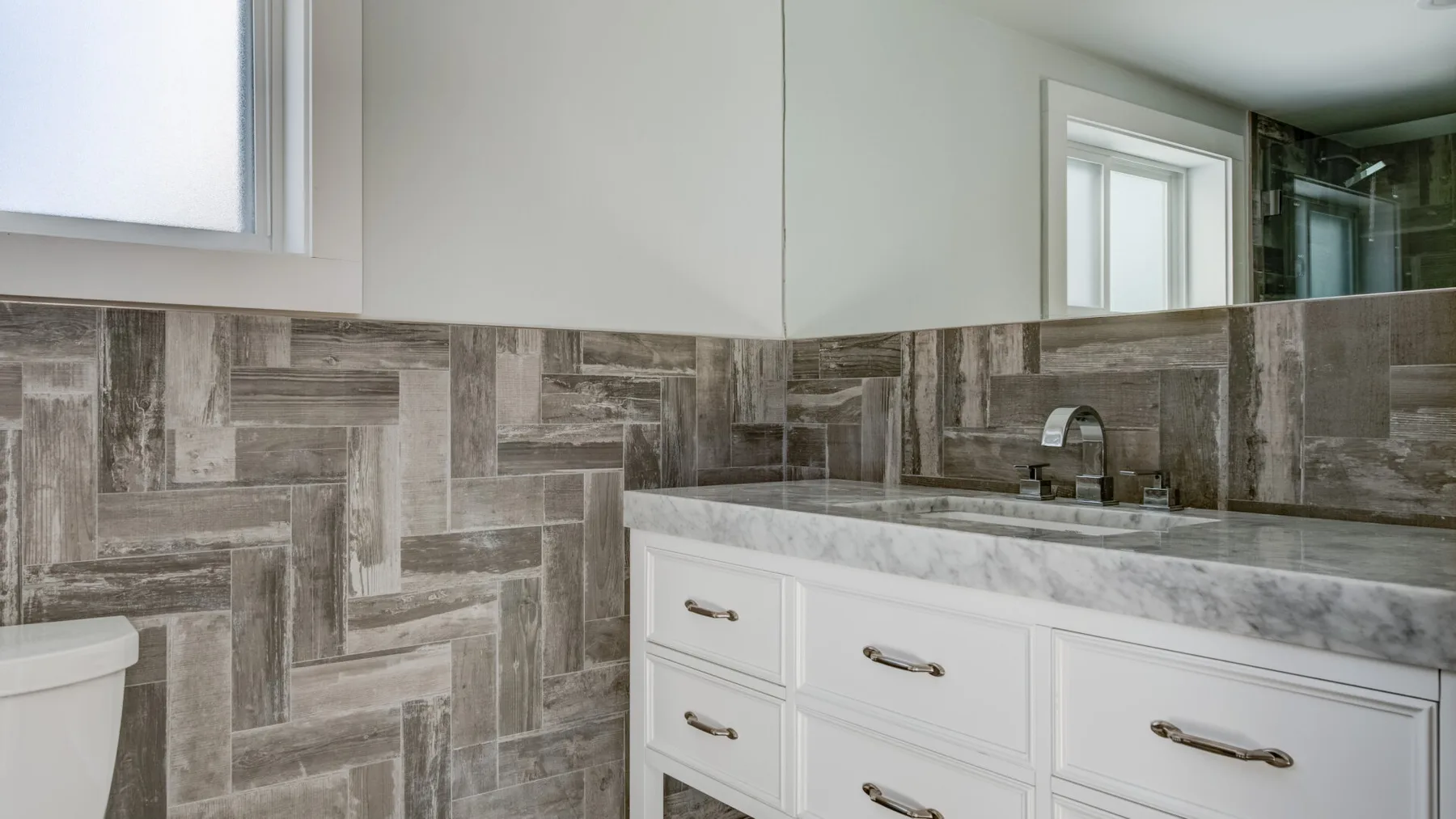 Un tocador de baño con lavabo y paredes de azulejos estampados.