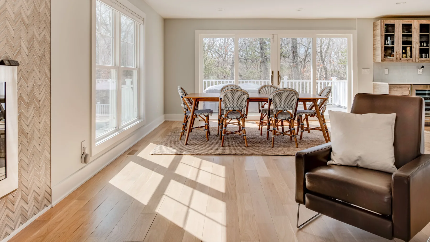 Un comedor luminoso con una mesa de madera junto a grandes ventanales.
