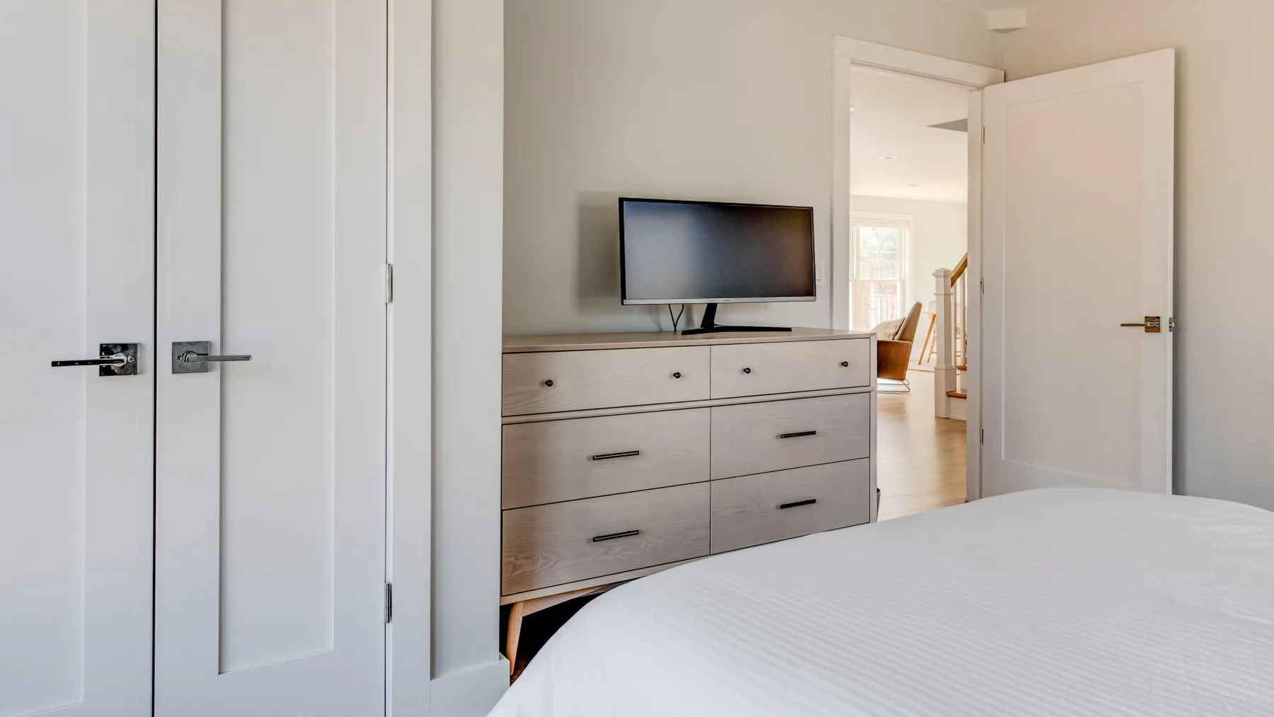 Un dormitorio con una cómoda, un televisor y una puerta abierta.