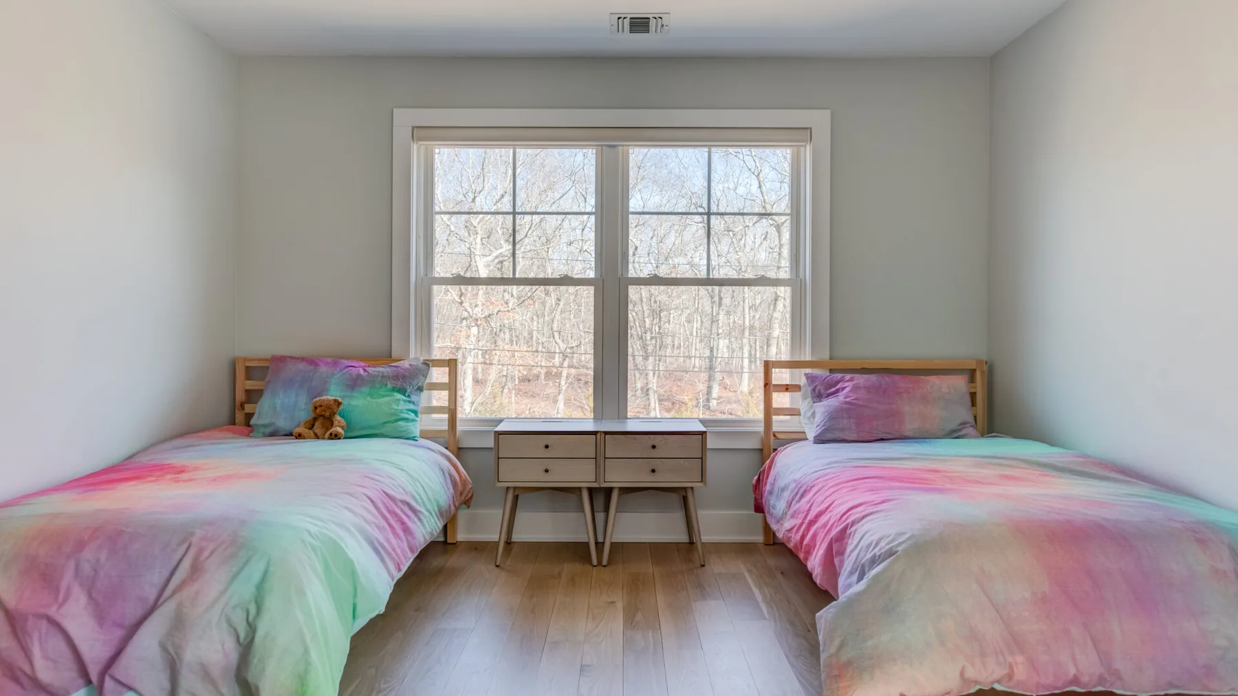 Un dormitorio con dos camas y una ventana con vistas a los árboles.