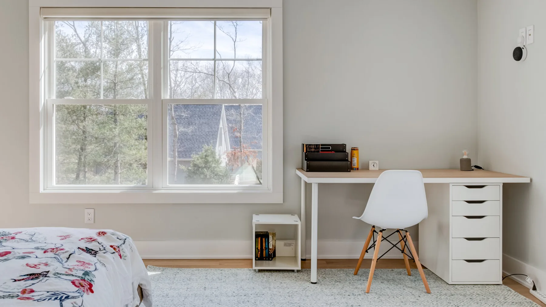 Un dormitorio con un escritorio y una silla junto a una ventana grande.