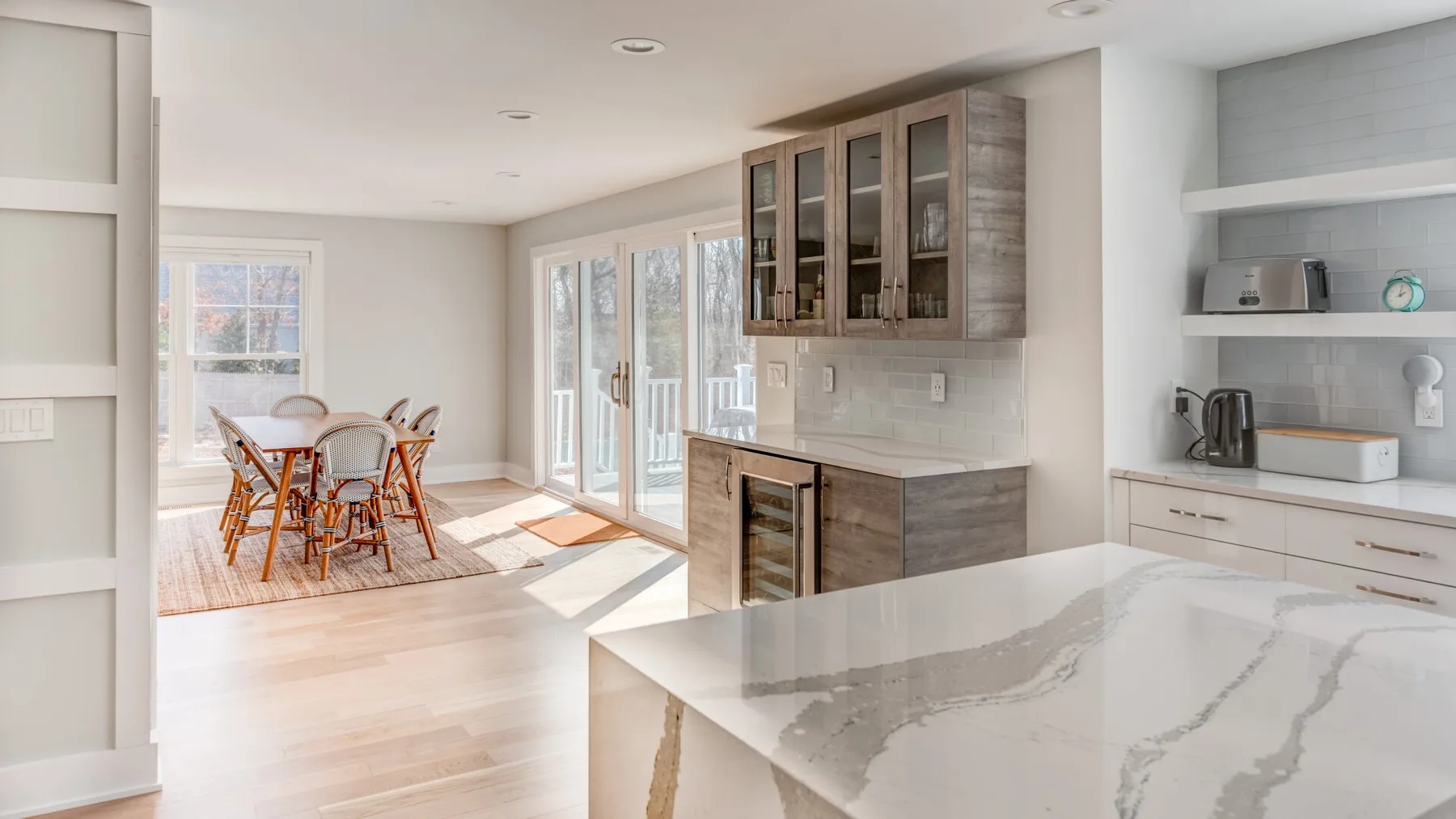 Una cocina y comedor luminosos con una isla de mármol y puertas de vidrio.