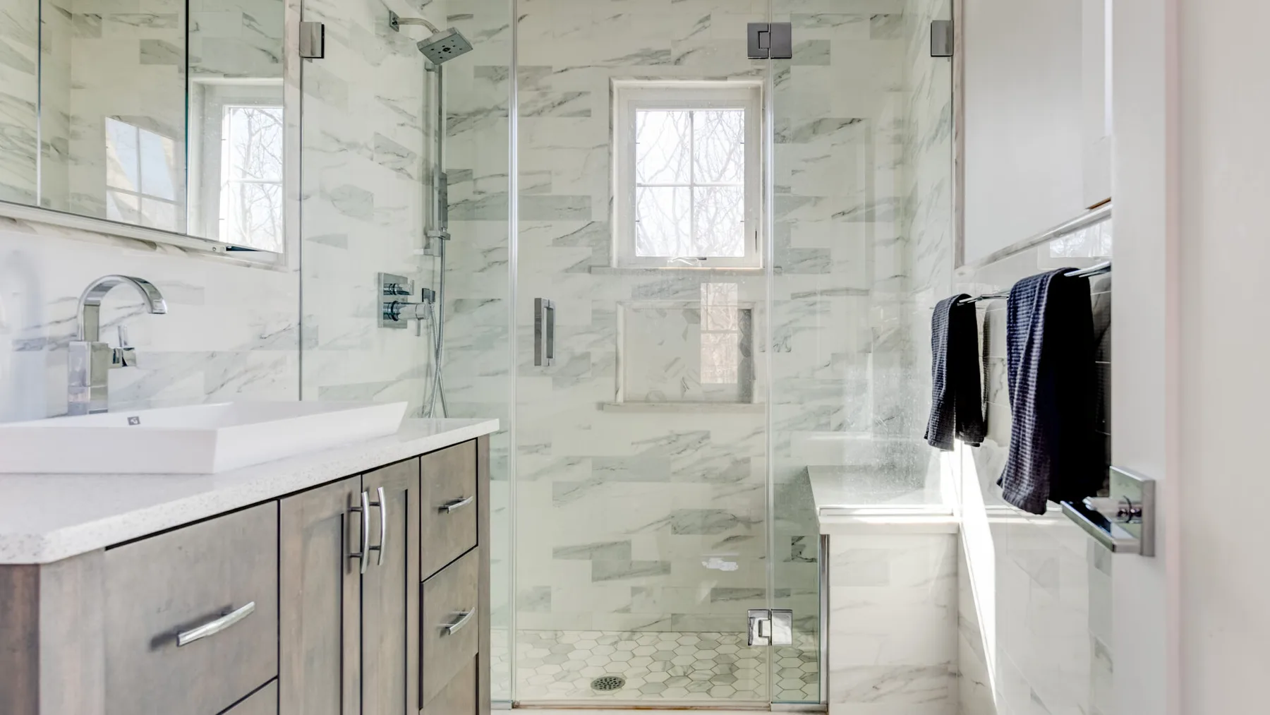 Un baño luminoso con ducha de vidrio, lavabo y ventana.