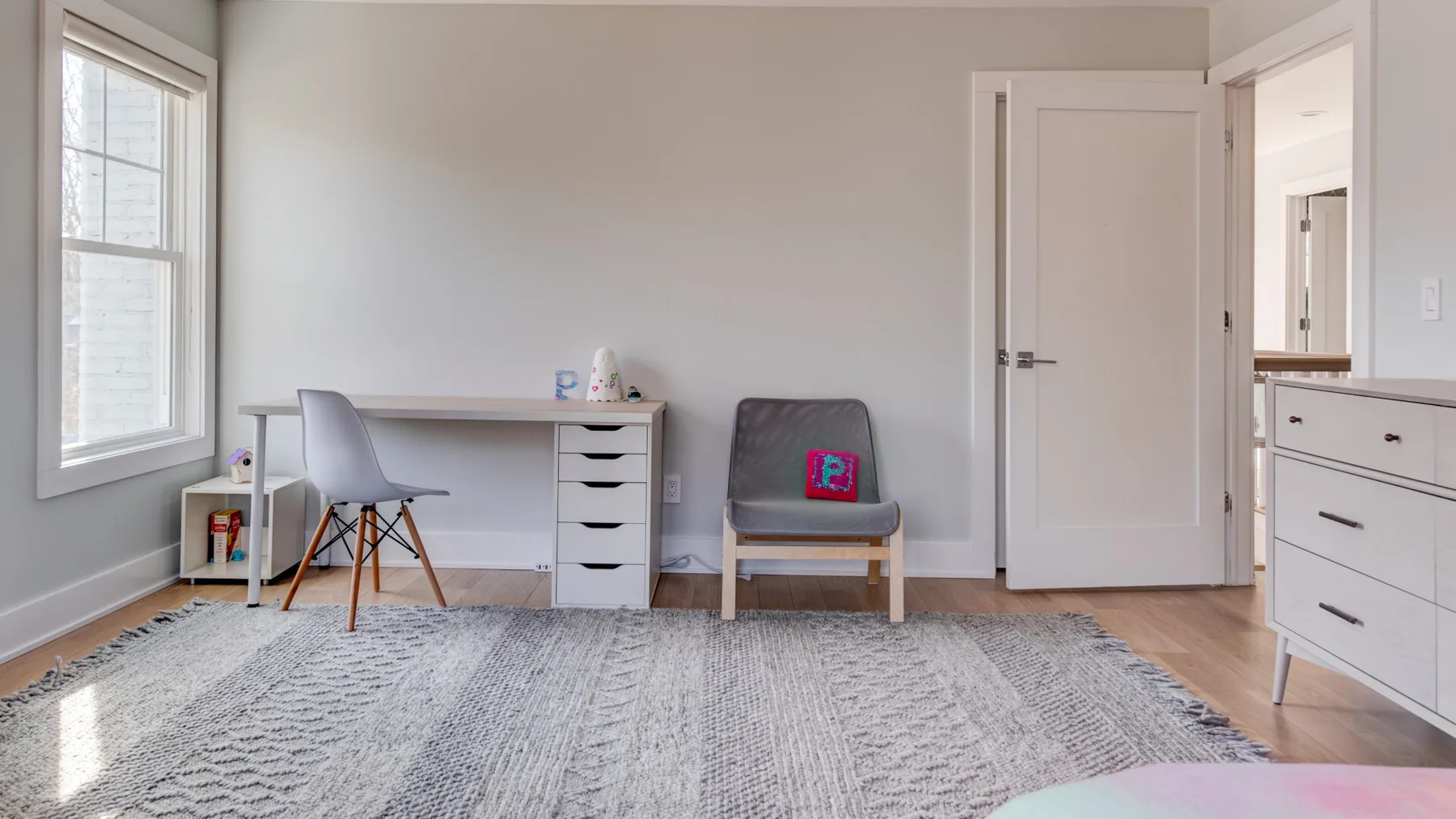 Una habitación luminosa con escritorio, asientos y una alfombra estampada grande.
