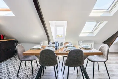 A dining area with a wooden table and chairs beneath skylights.