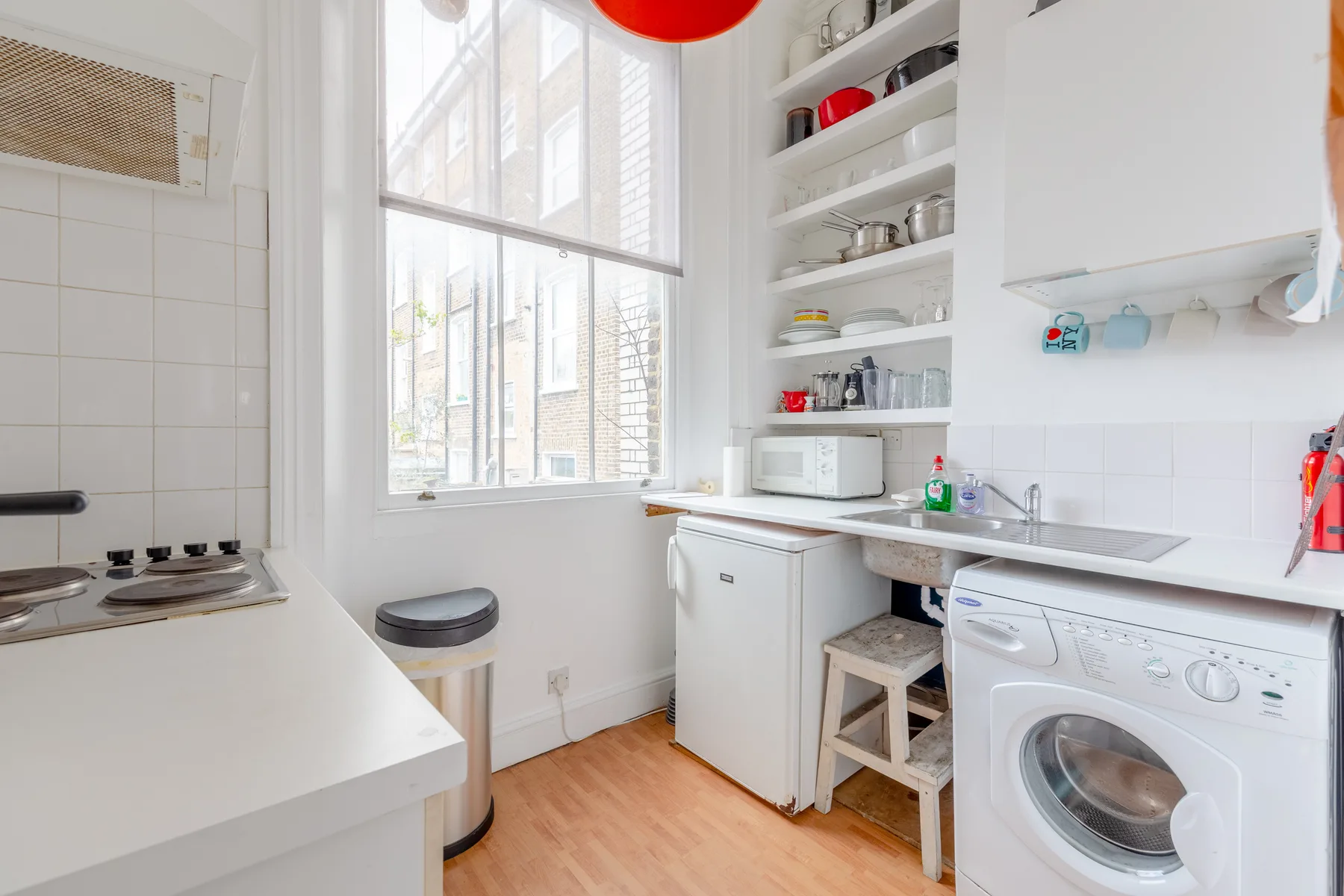 A bright kitchen with a large window, countertop, and washing machine.