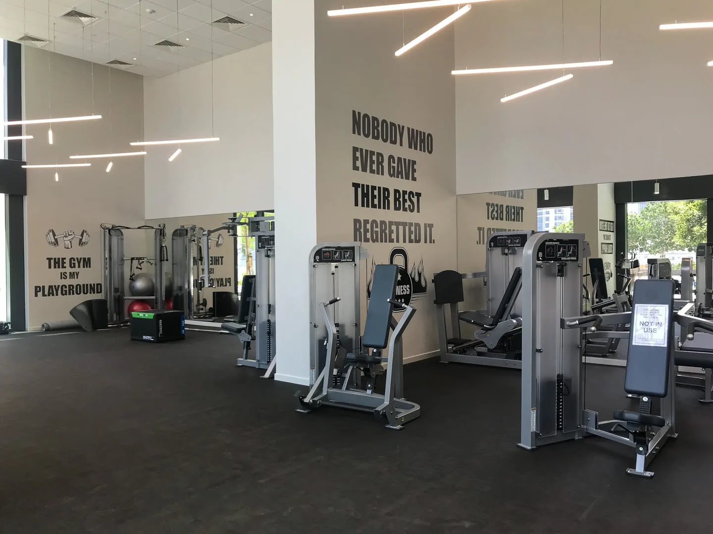 Un gimnasio con máquinas de ejercicio y frases motivadoras en las paredes.