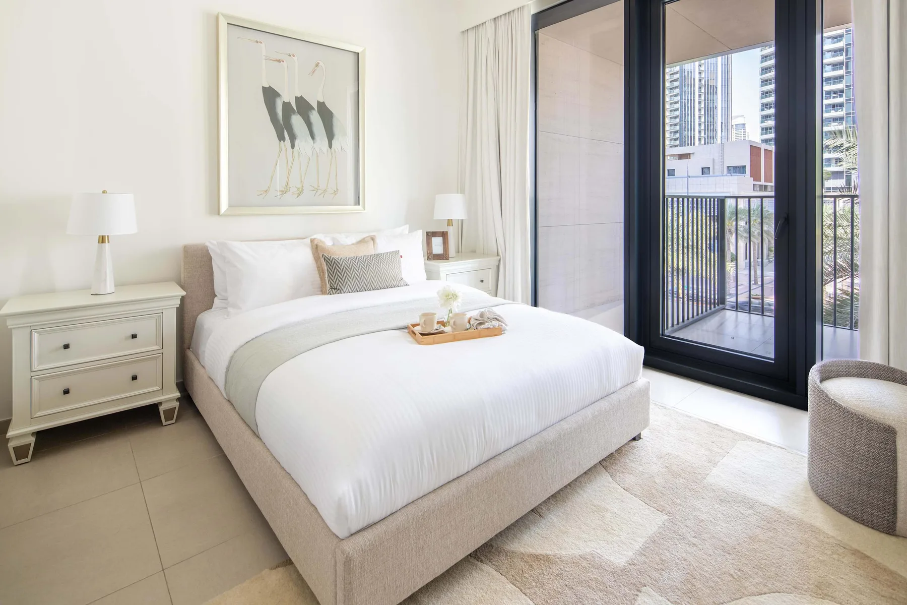 Un dormitorio luminoso con una cama tendida junto a grandes ventanales al balcón.