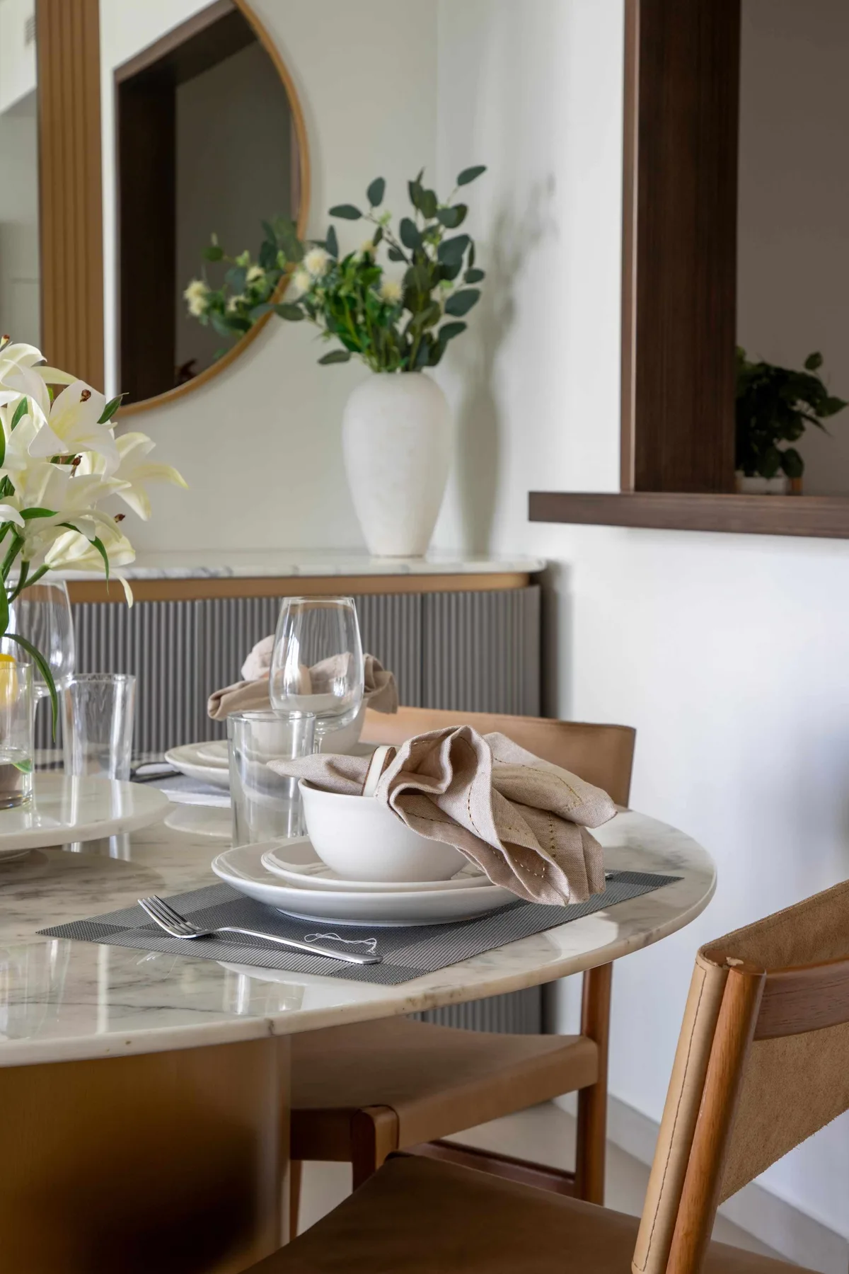 Una mesa de comedor está preparada con platos, vasos y un paño doblado.