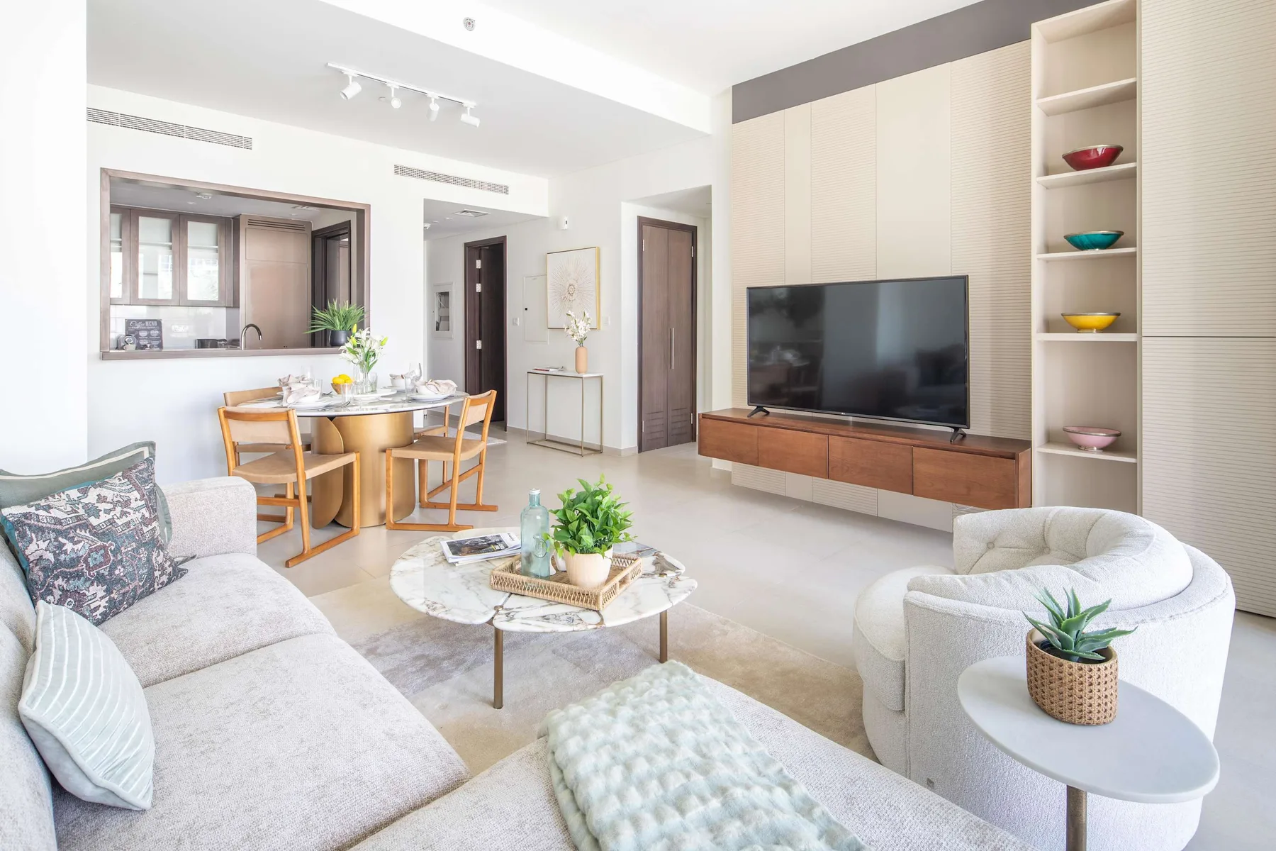 Una sala de estar luminosa con asientos alrededor de una mesa de centro y un televisor.