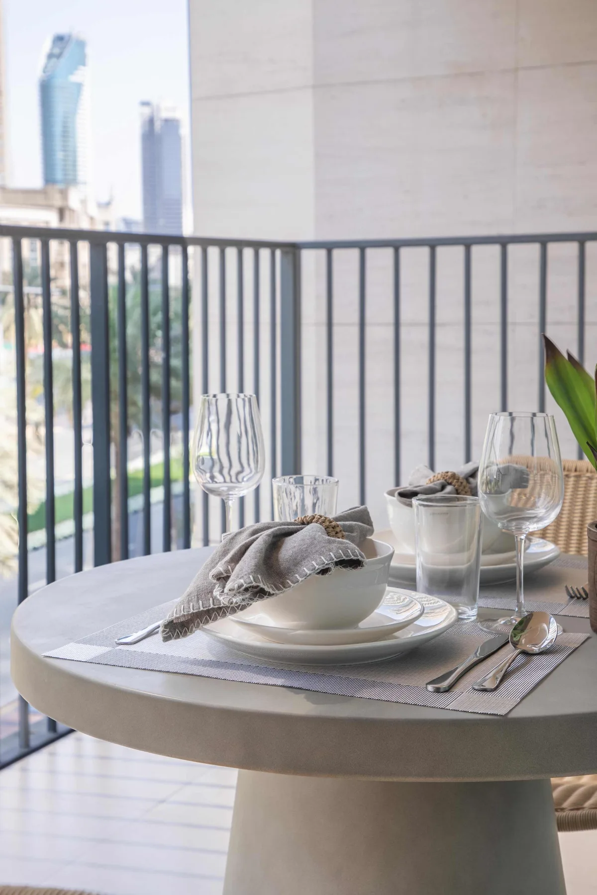 Una mesa de comedor puesta en un balcón da a edificios cercanos.