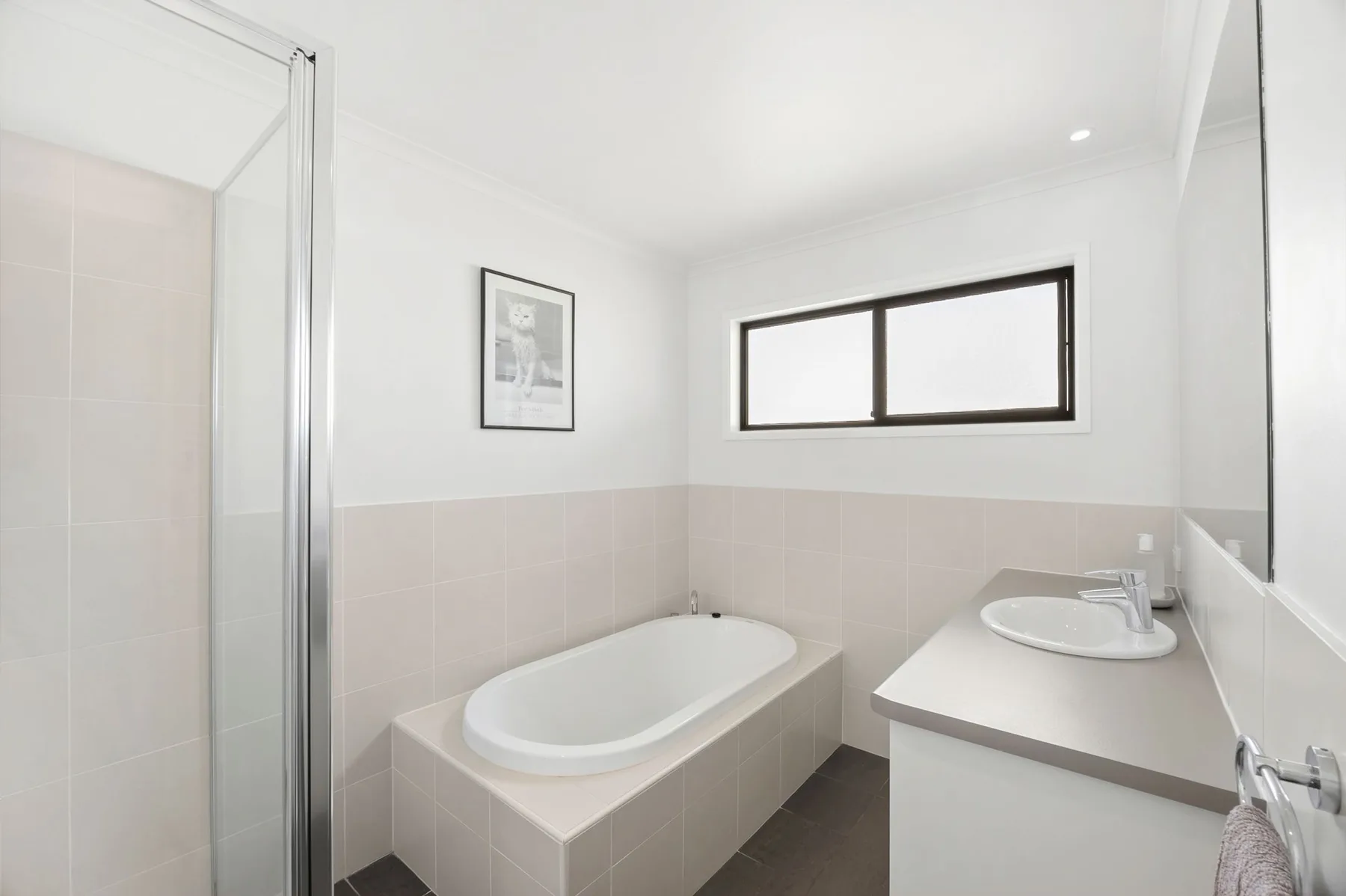 Un baño luminoso con bañera, lavabo y ventana.