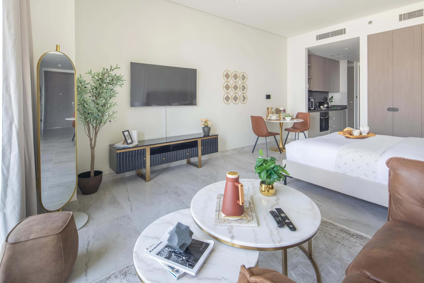 Un dormitorio luminoso con cama, zona de estar y televisor.