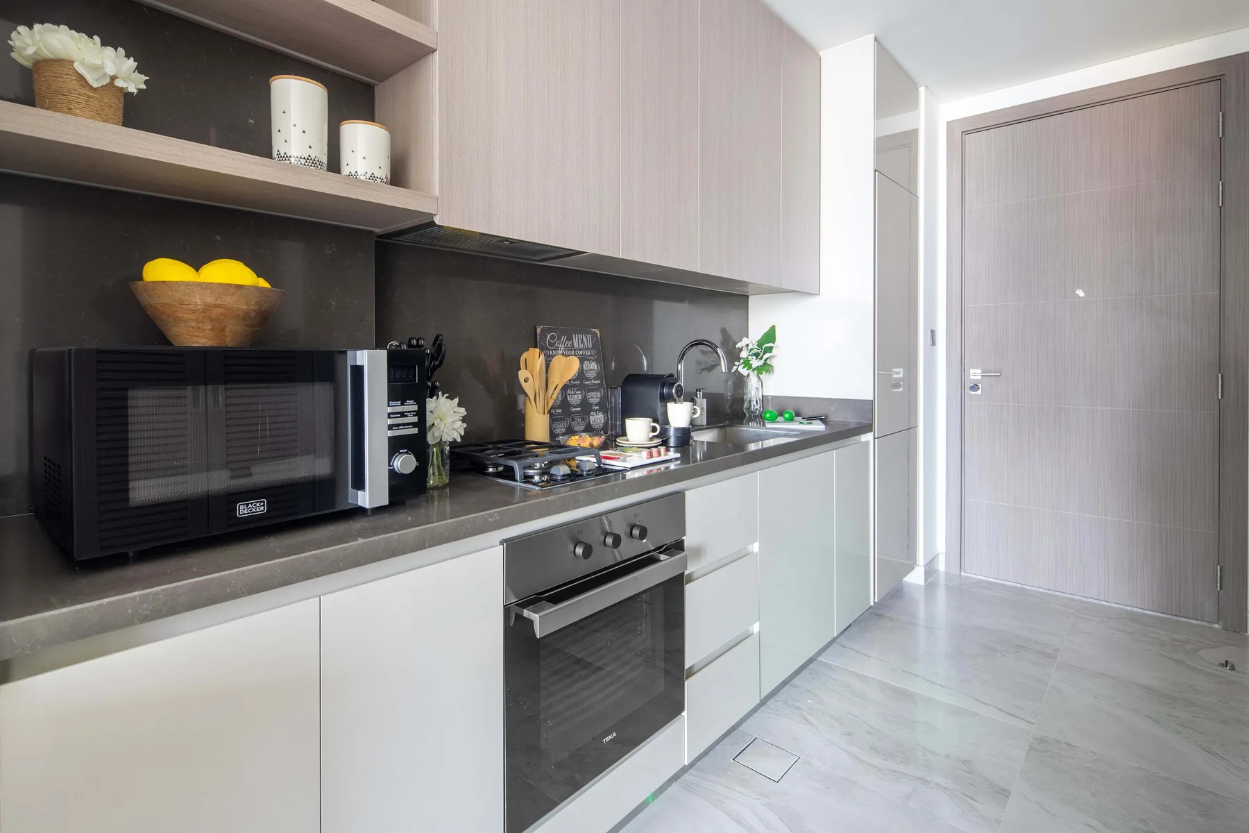 Una cocina moderna con microondas, cocina y gabinetes de color claro.