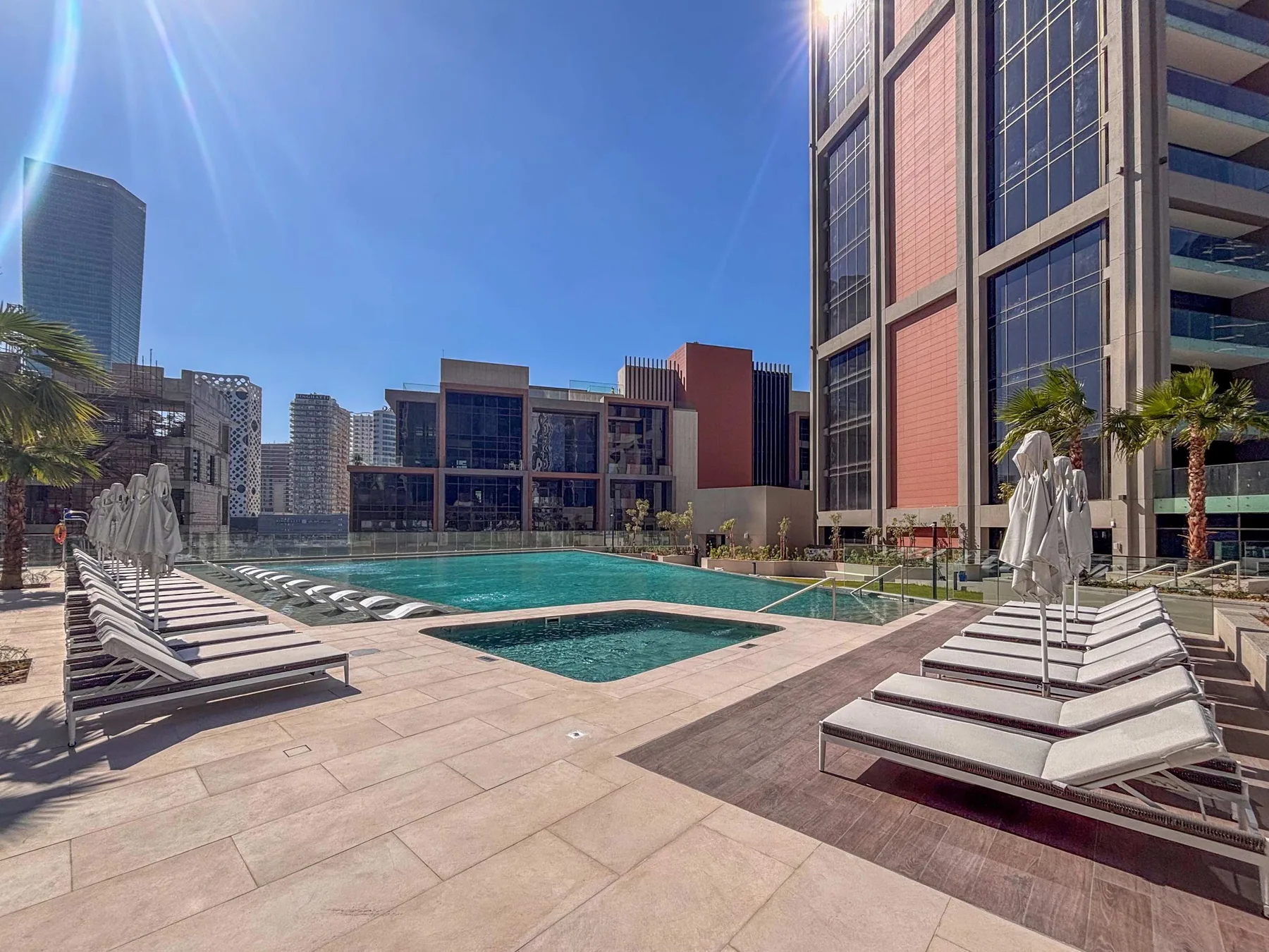 Una piscina al aire libre está rodeada de asientos y edificios modernos.
