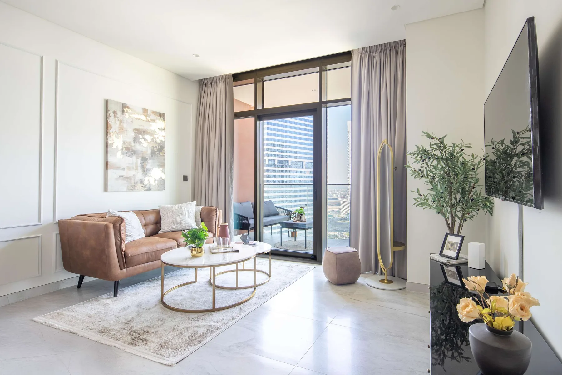 Una sala luminosa con una zona de estar junto a ventanas altas y cortinas.