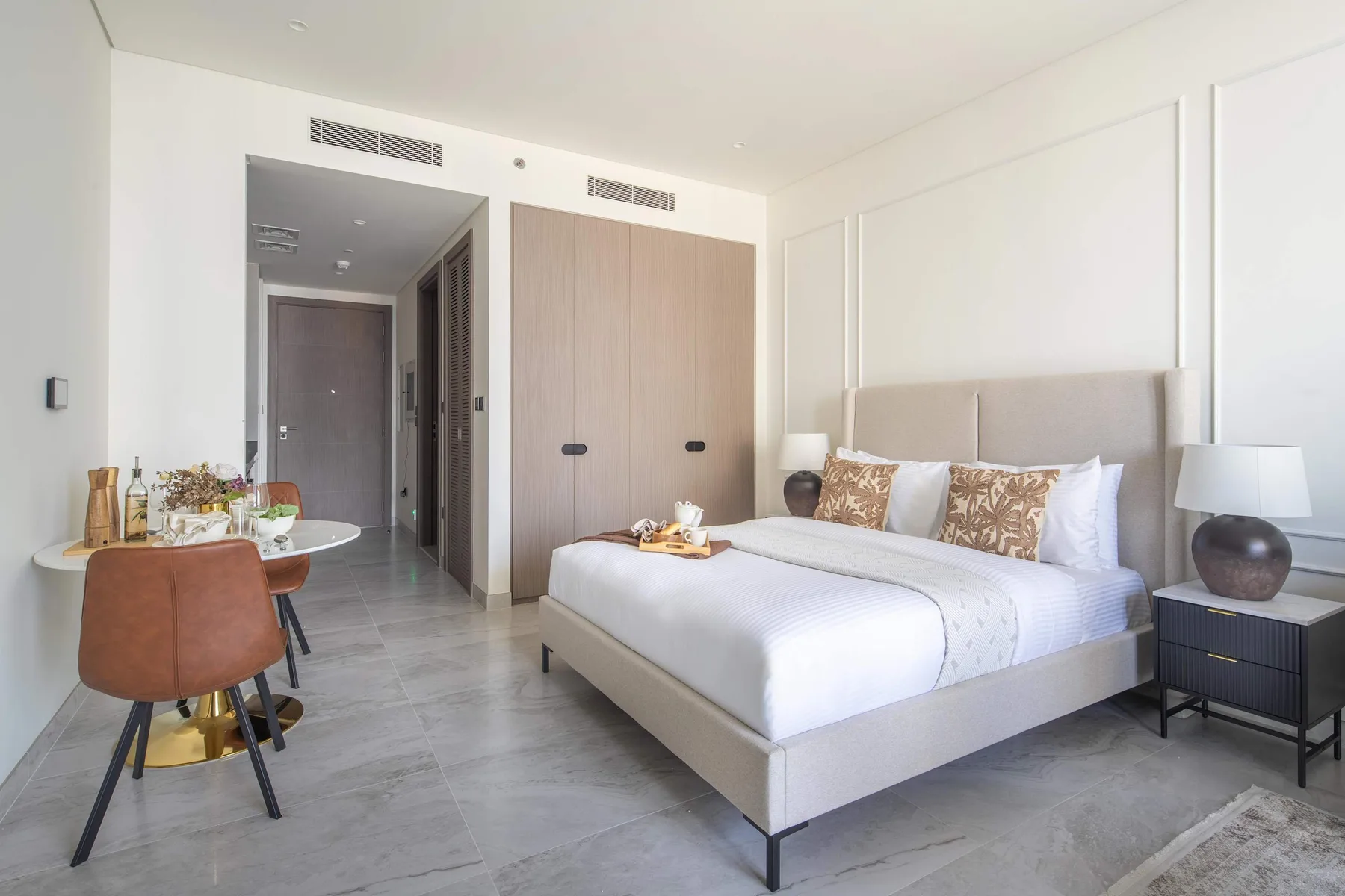 Un dormitorio luminoso con una cama grande y una pequeña mesa de comedor.
