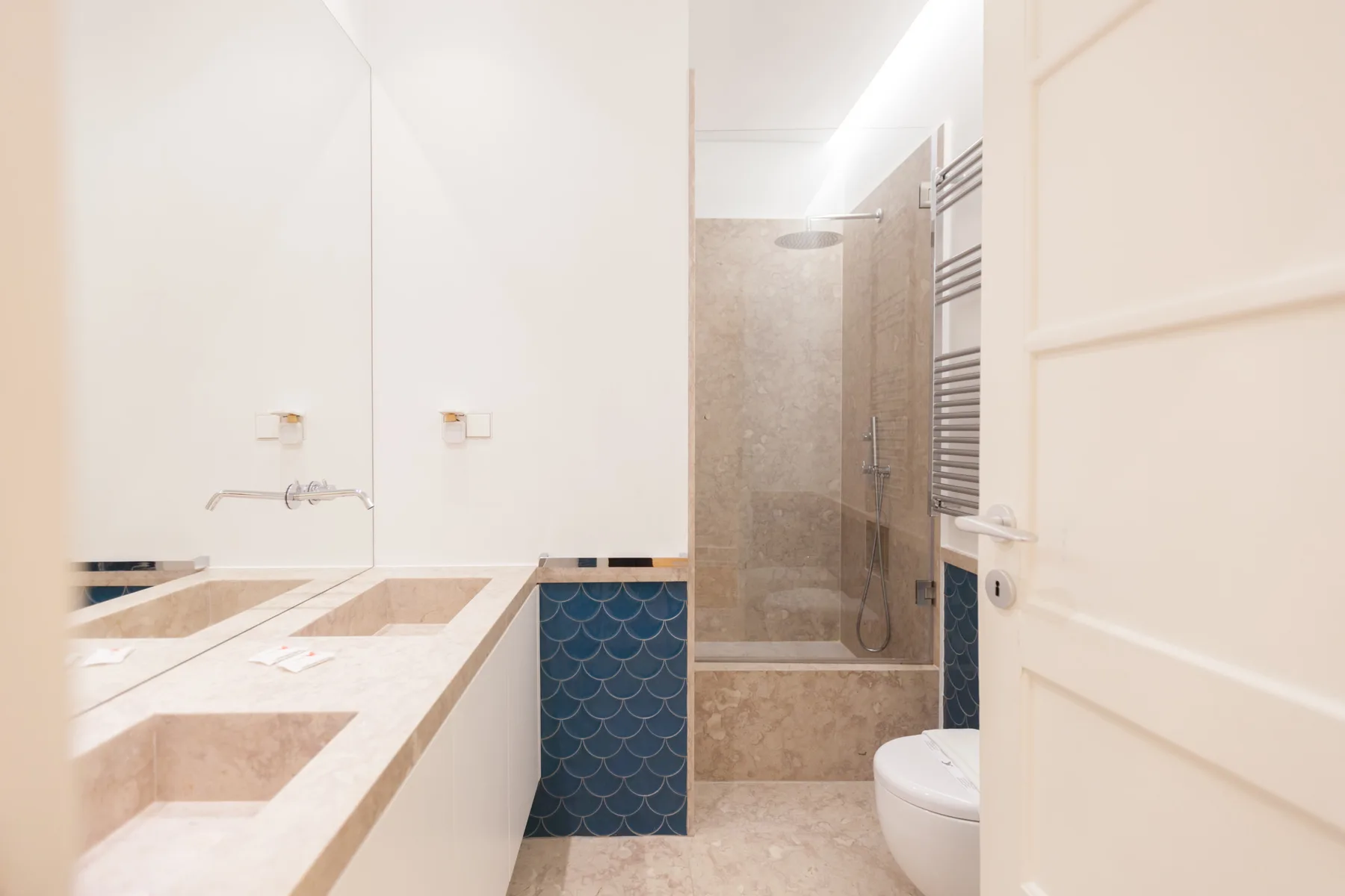 Un baño con una encimera larga y una ducha a ras de suelo.