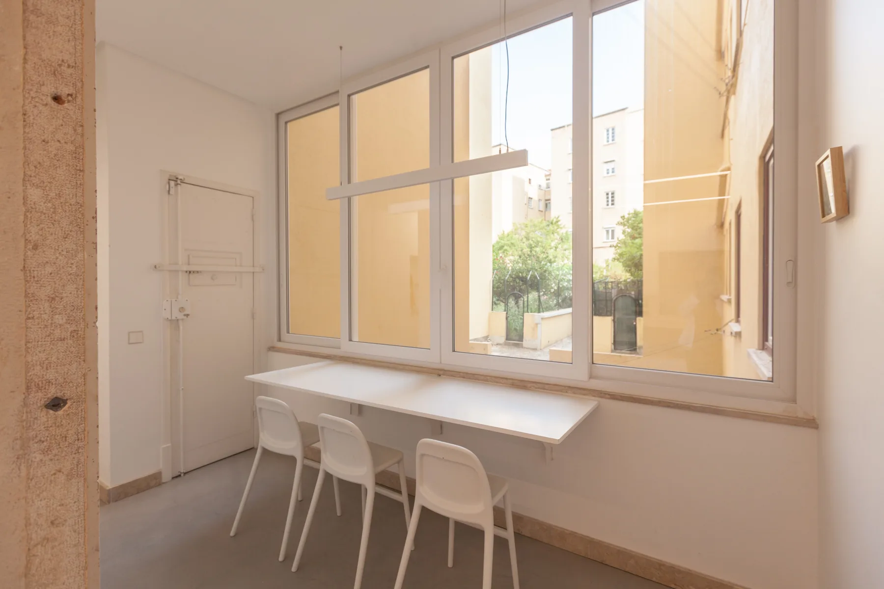 Una luminosa zona interior con una mesa larga junto a grandes ventanas.