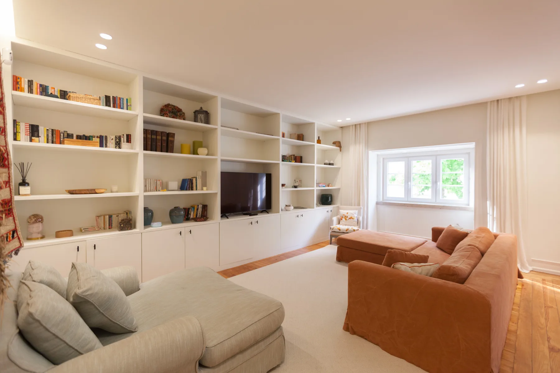Sala de estar con estanterías empotradas, televisor y asientos.