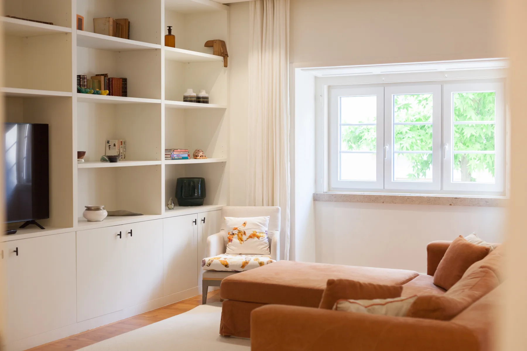 Una sala luminosa con estanterías empotradas, asientos y una ventana amplia.