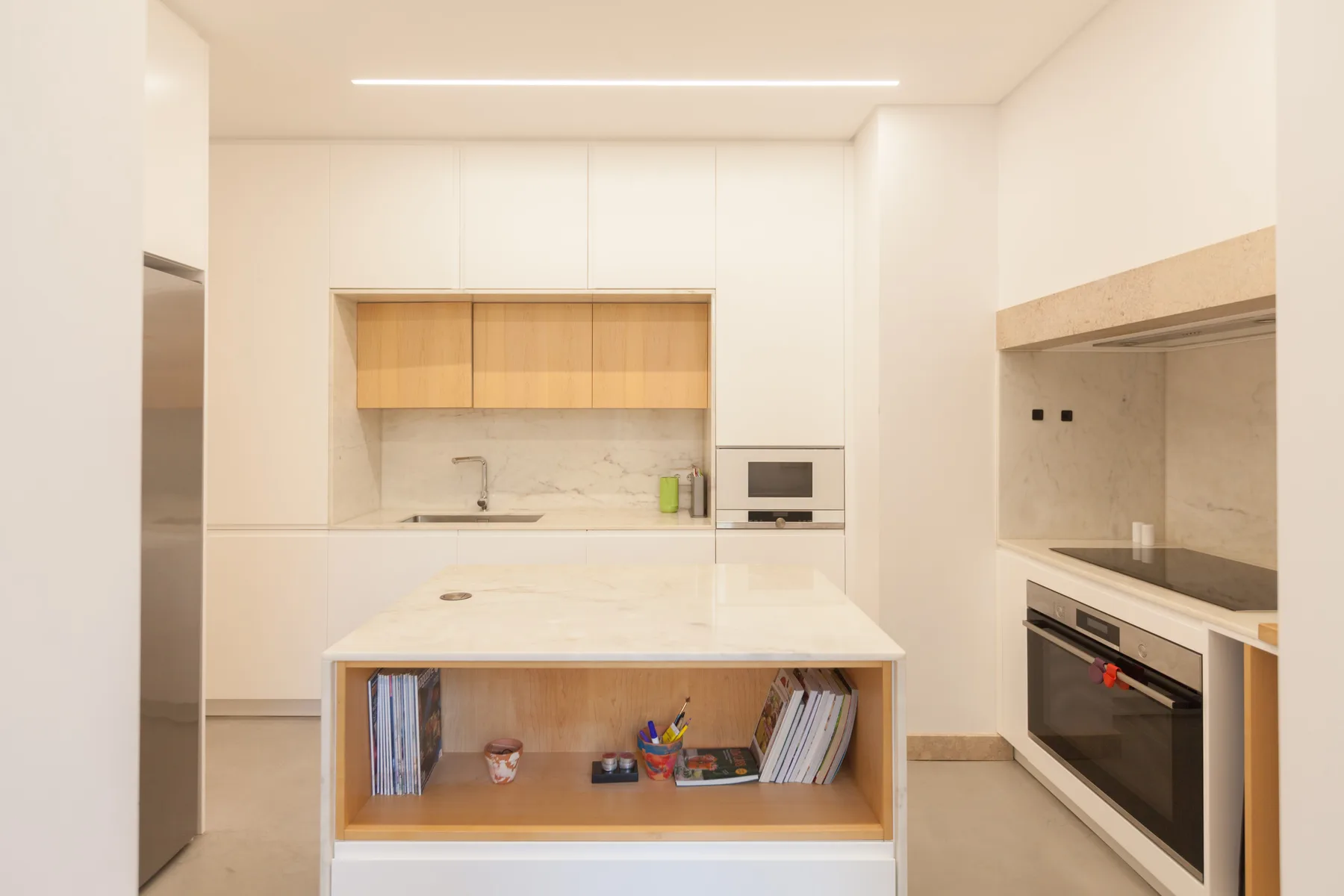 Una cocina moderna y luminosa con una isla central, horno integrado y armarios claros.