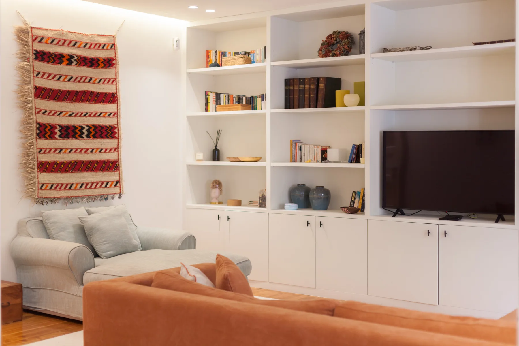 Un salón con asientos, un televisor y estanterías empotradas.