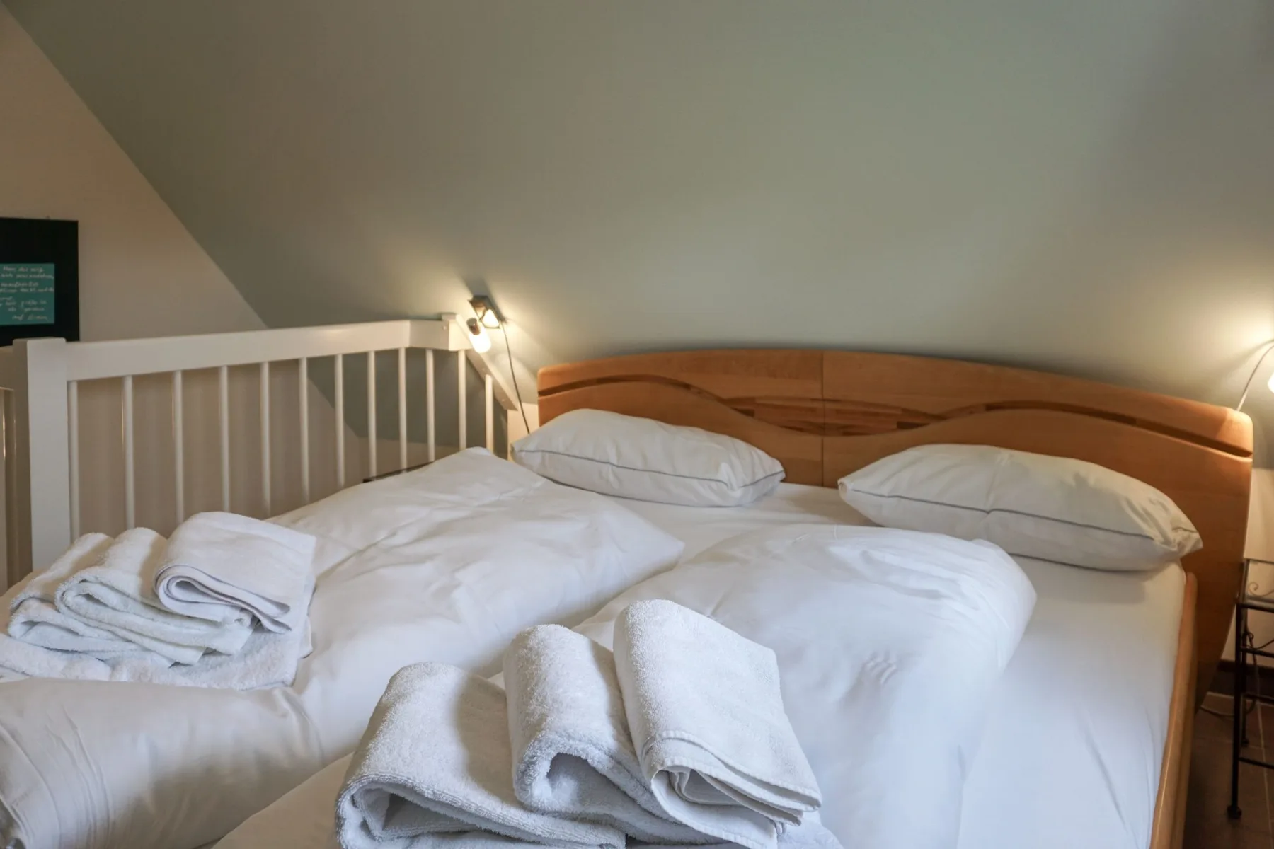 A bedroom with a bed, white bedding, and folded towels.