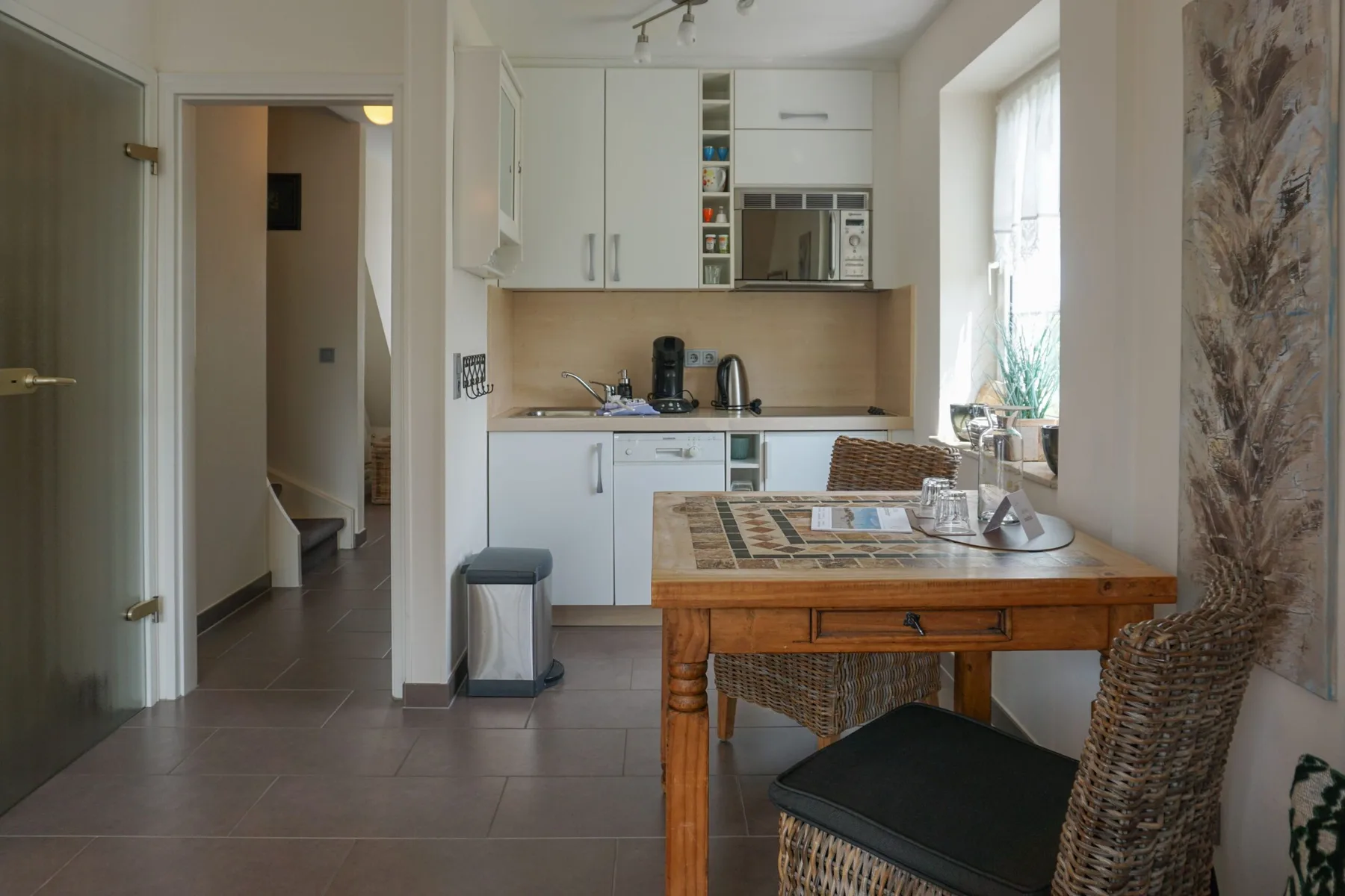 A bright kitchen and dining area with a wooden table and woven seating.