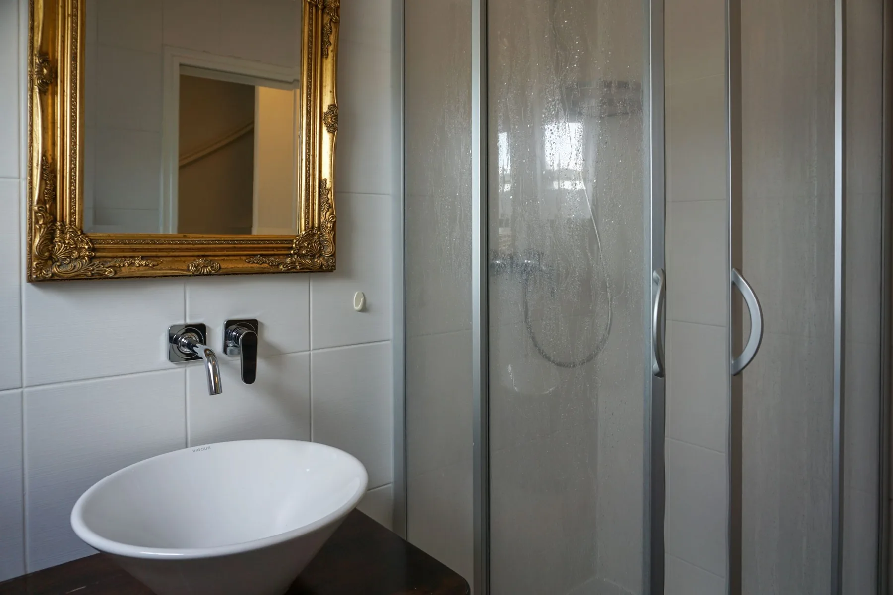 A tiled bathroom with a sink, wall mirror, and glass shower.