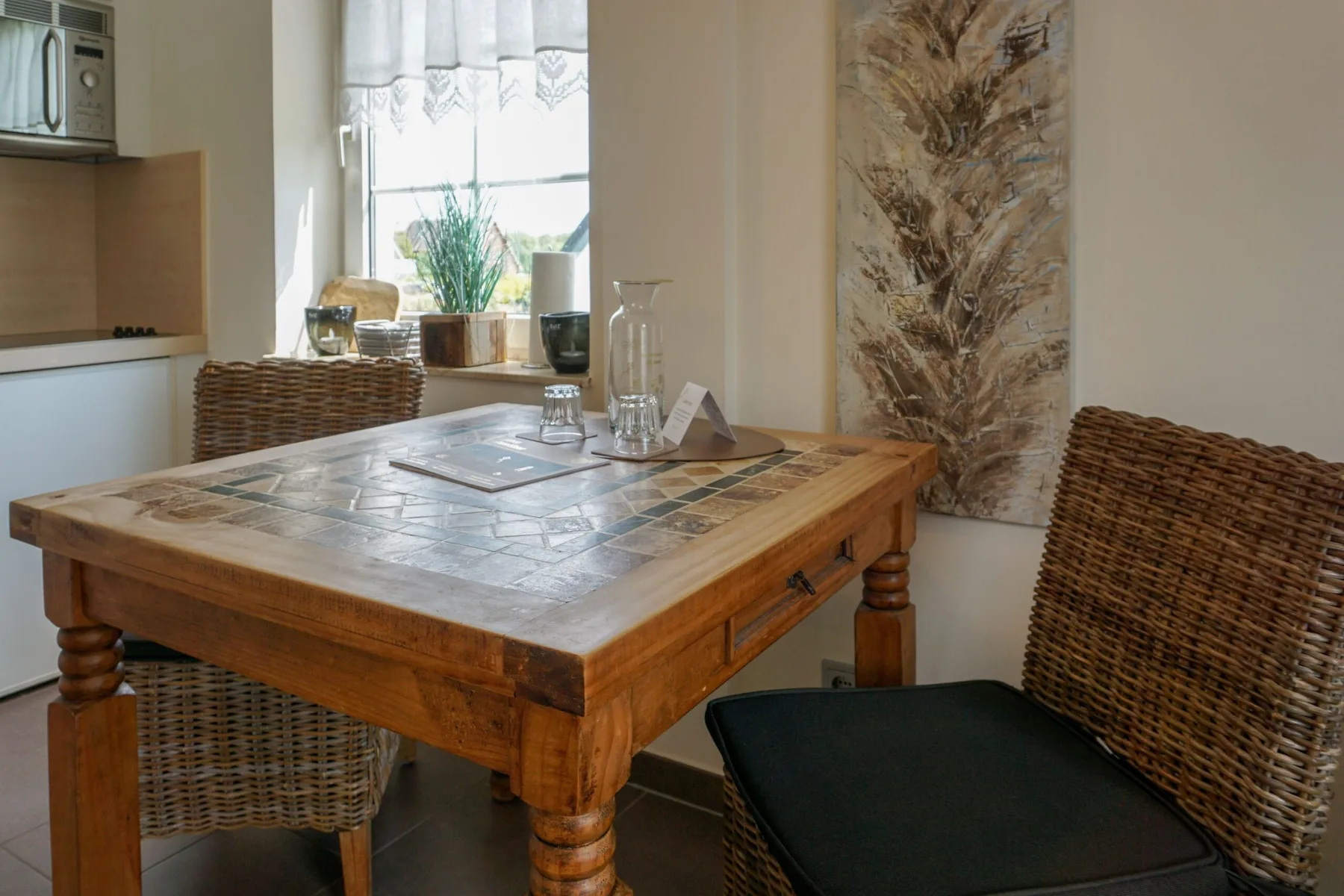 A dining area with a wooden table and woven seating beside a bright window.