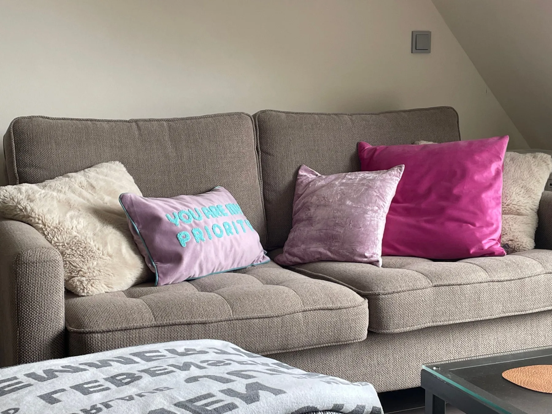 A gray sofa with colorful cushions sits beside a low coffee table.