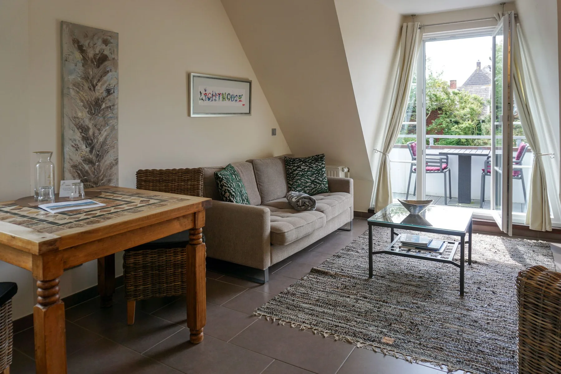 A bright living room with a sofa, coffee table, and open balcony doors.