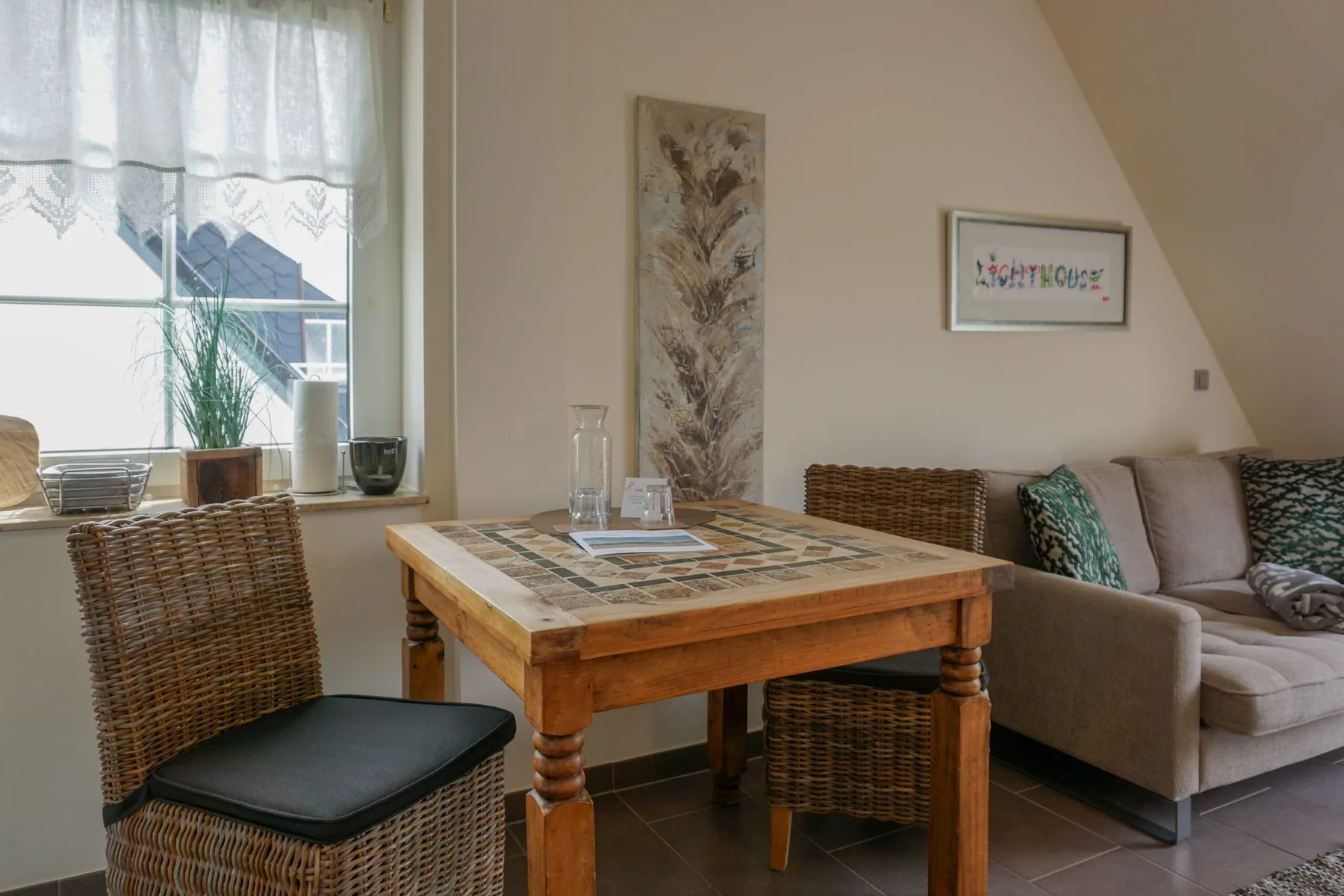 A dining table and wicker seating sit beside a bright window in the living area.