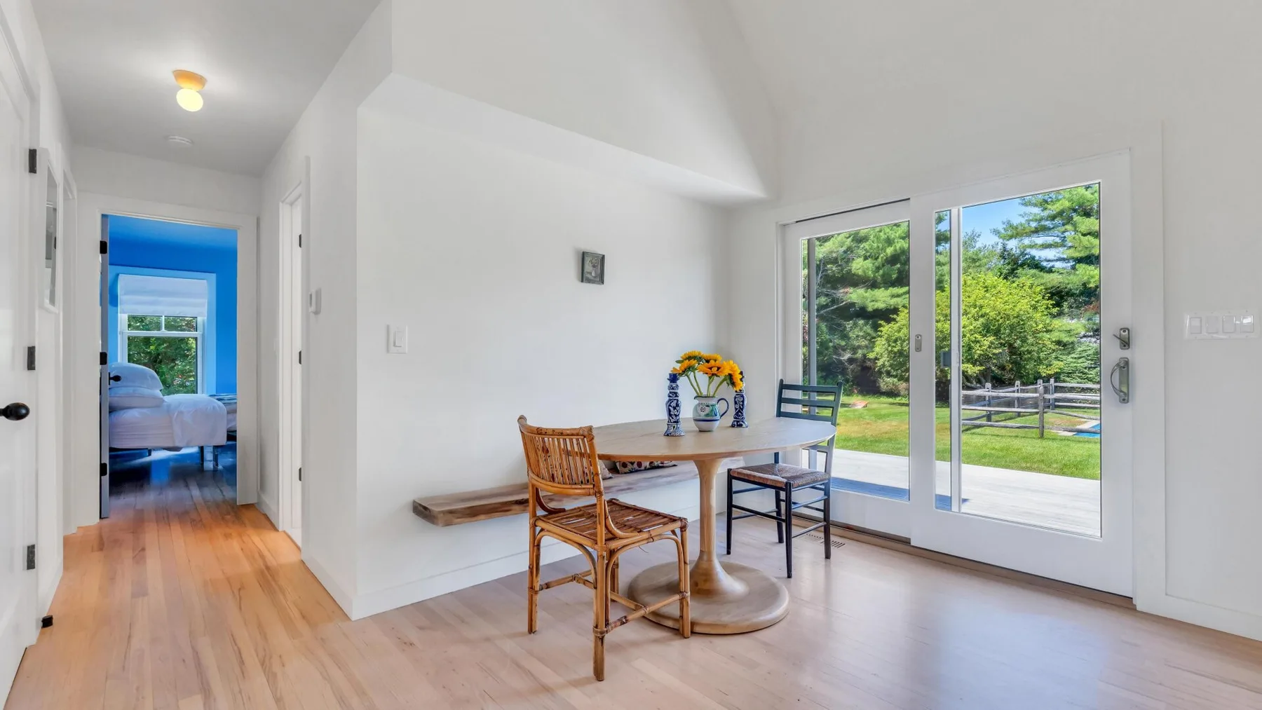 Un comedor luminoso con una mesa de madera junto a grandes puertas de vidrio con vistas a la vegetación.