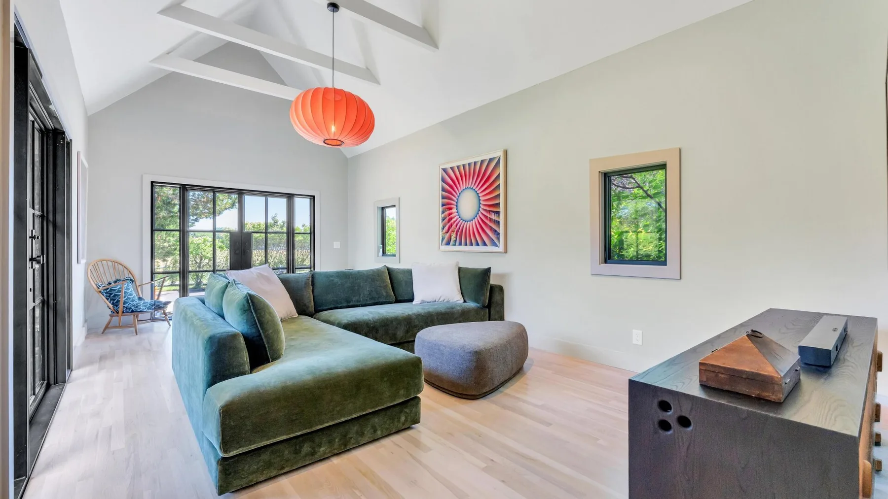 Una sala luminosa con un sofá seccional verde y arte colorido en la pared.