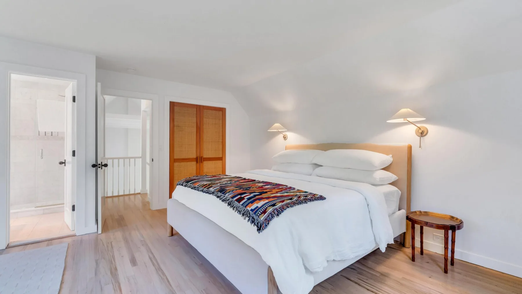Un dormitorio con una cama bien tendida y una manta estampada de colores.