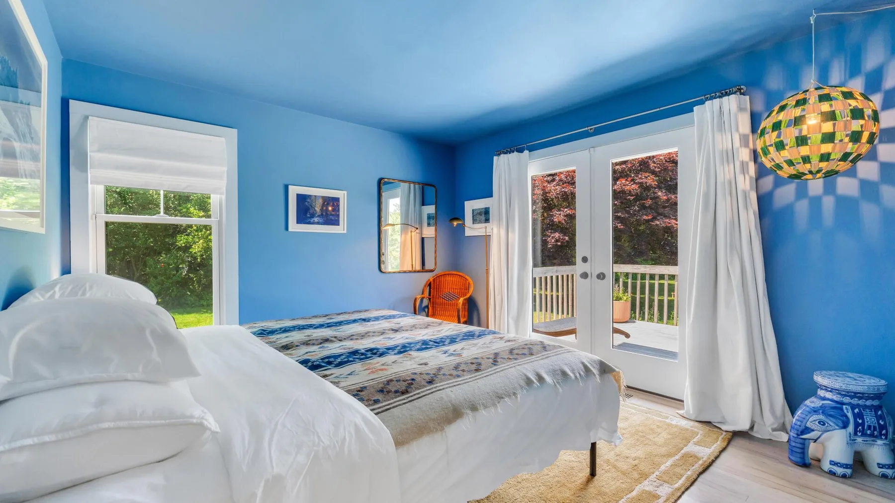 Un dormitorio azul con una cama y puertas de vidrio que dan a un balcón.