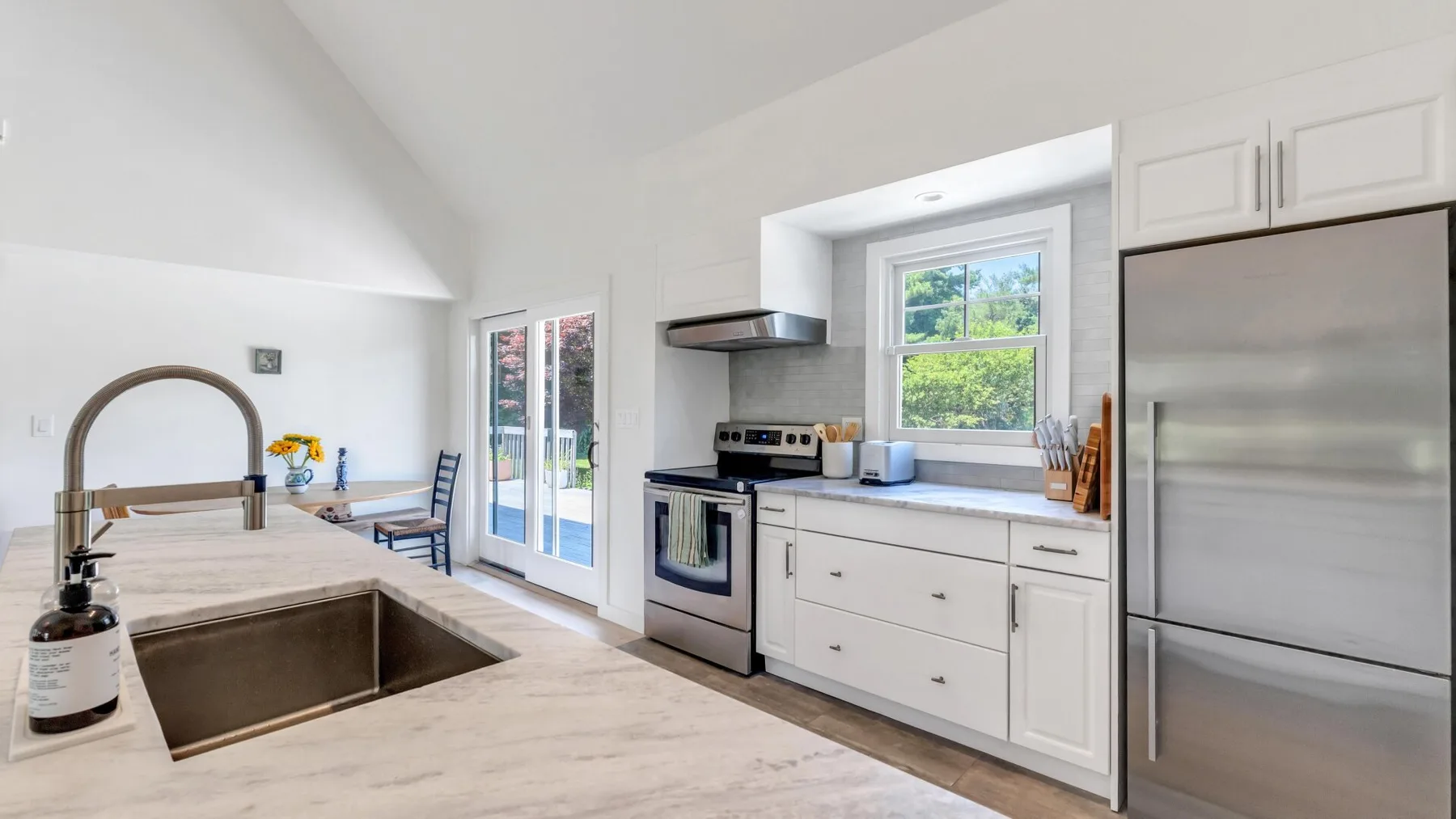 Una cocina luminosa con un fregadero grande, gabinetes blancos y una ventana sobre la encimera.