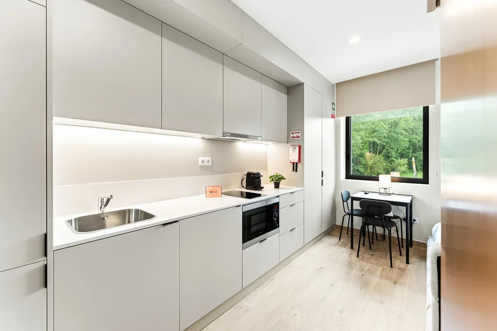 A modern kitchen with a dining table beside a large window.