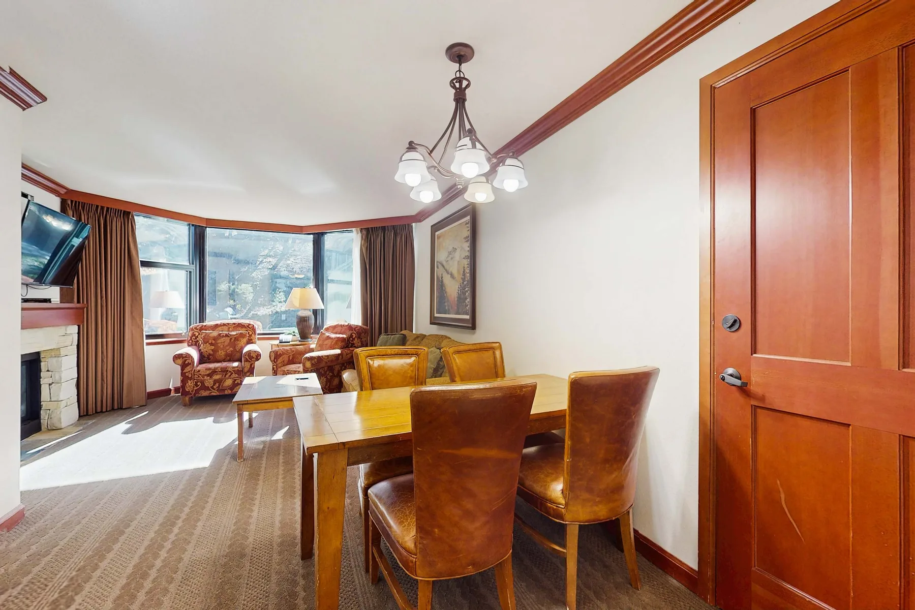 A dining area with wooden seating beside large windows.