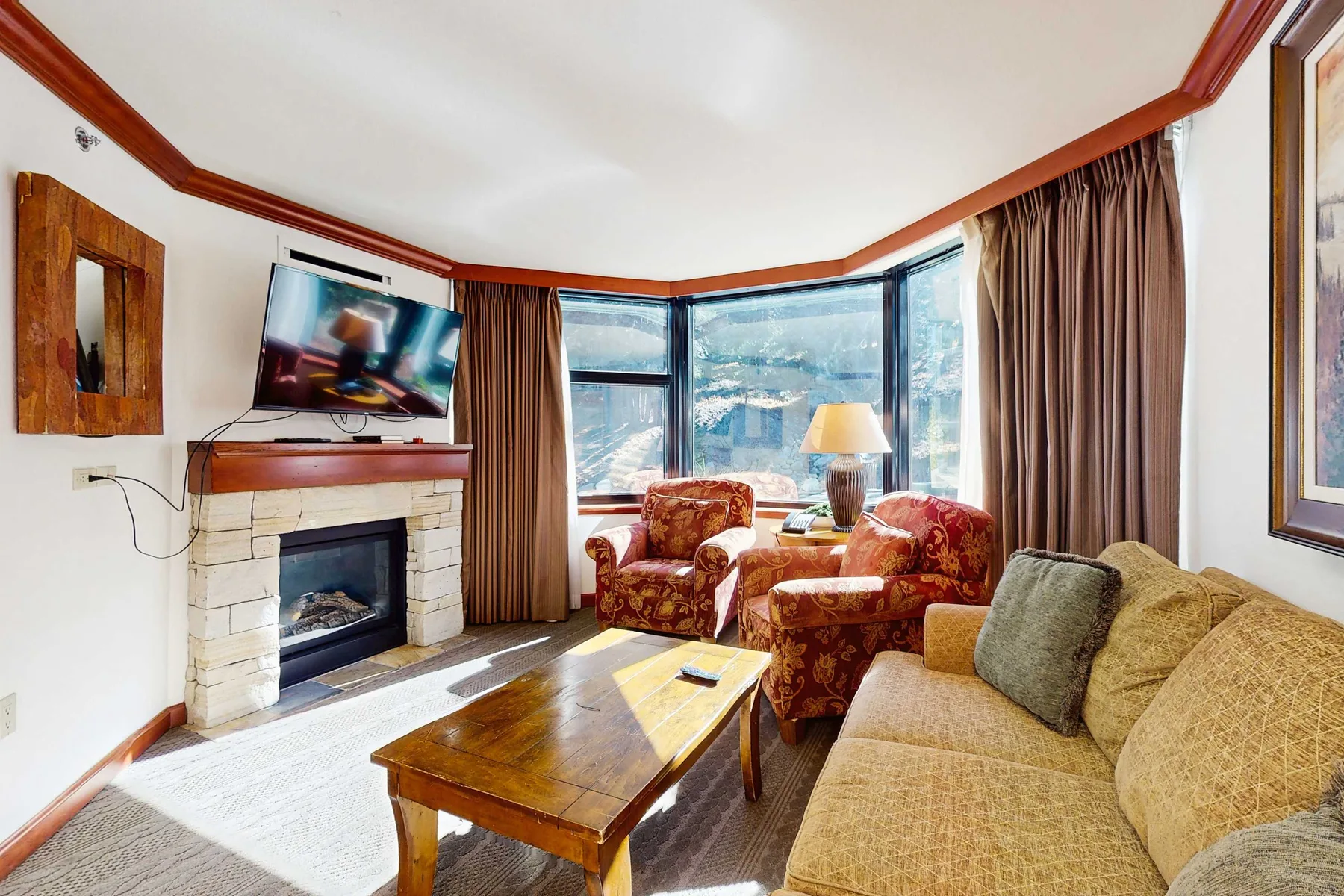 A living room with seating, a fireplace, and large windows overlooking the city.
