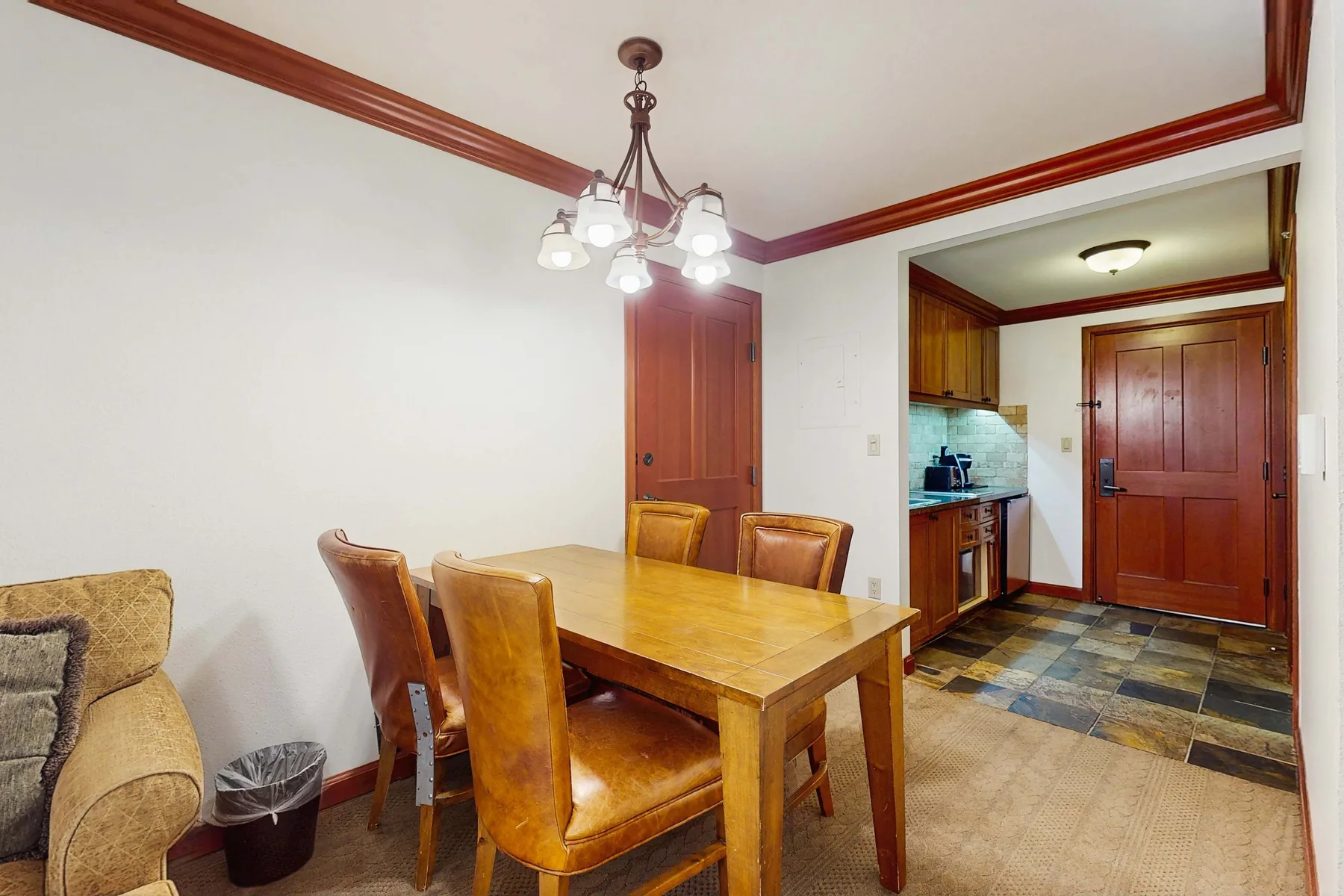 A dining area with a wooden table and chairs beside an open kitchen.
