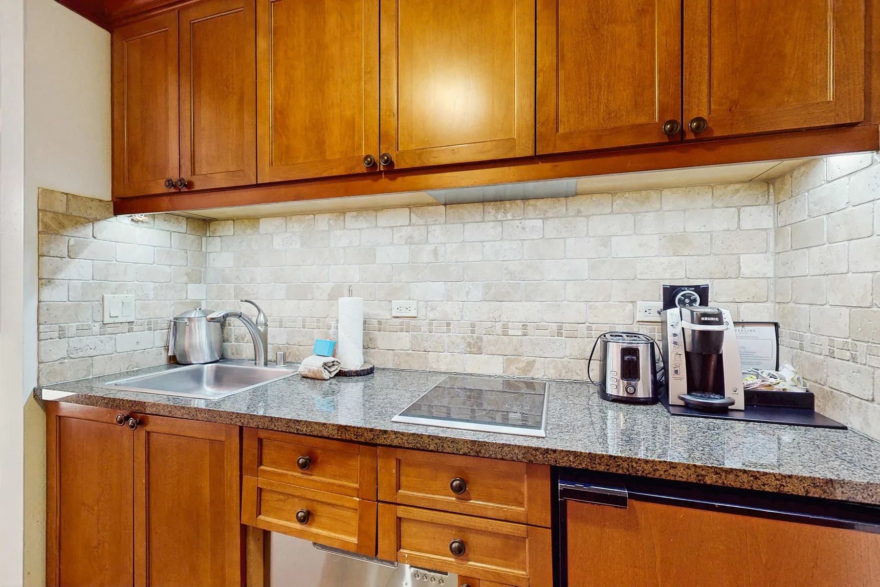 A kitchen counter with wooden cabinets, a sink, and small appliances.