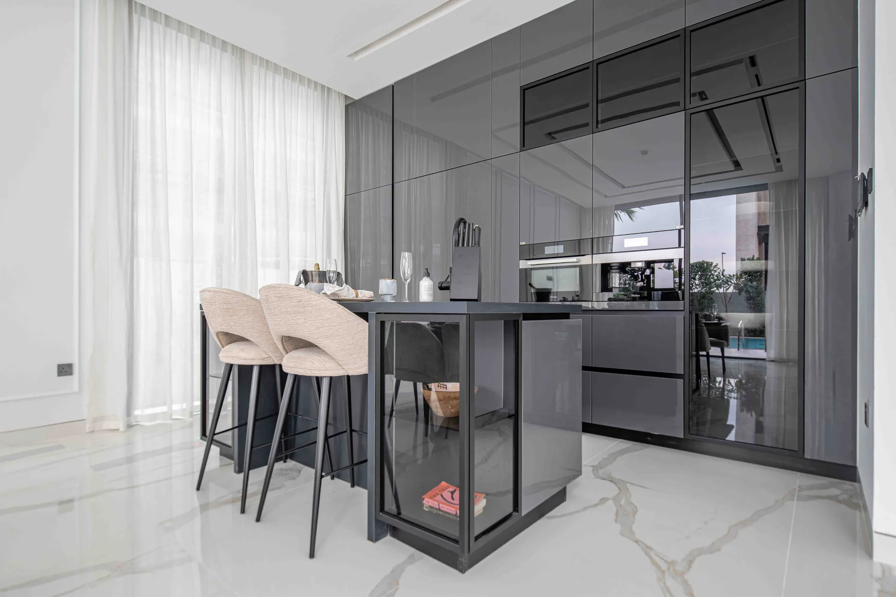 Una cocina moderna con isla central, asientos de barra y gabinetes oscuros.