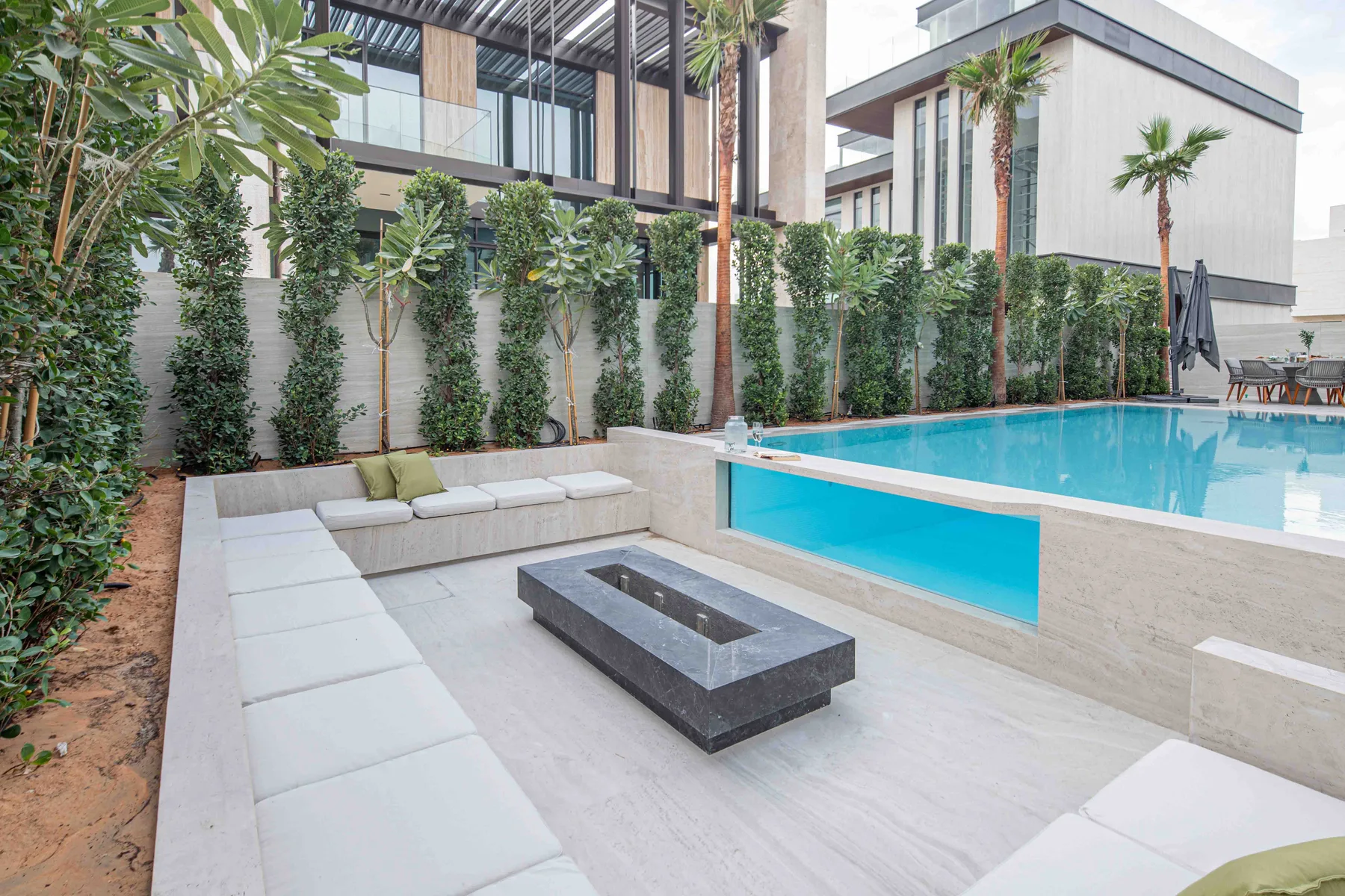 Una piscina exterior junto a una zona pavimentada con asientos integrados.