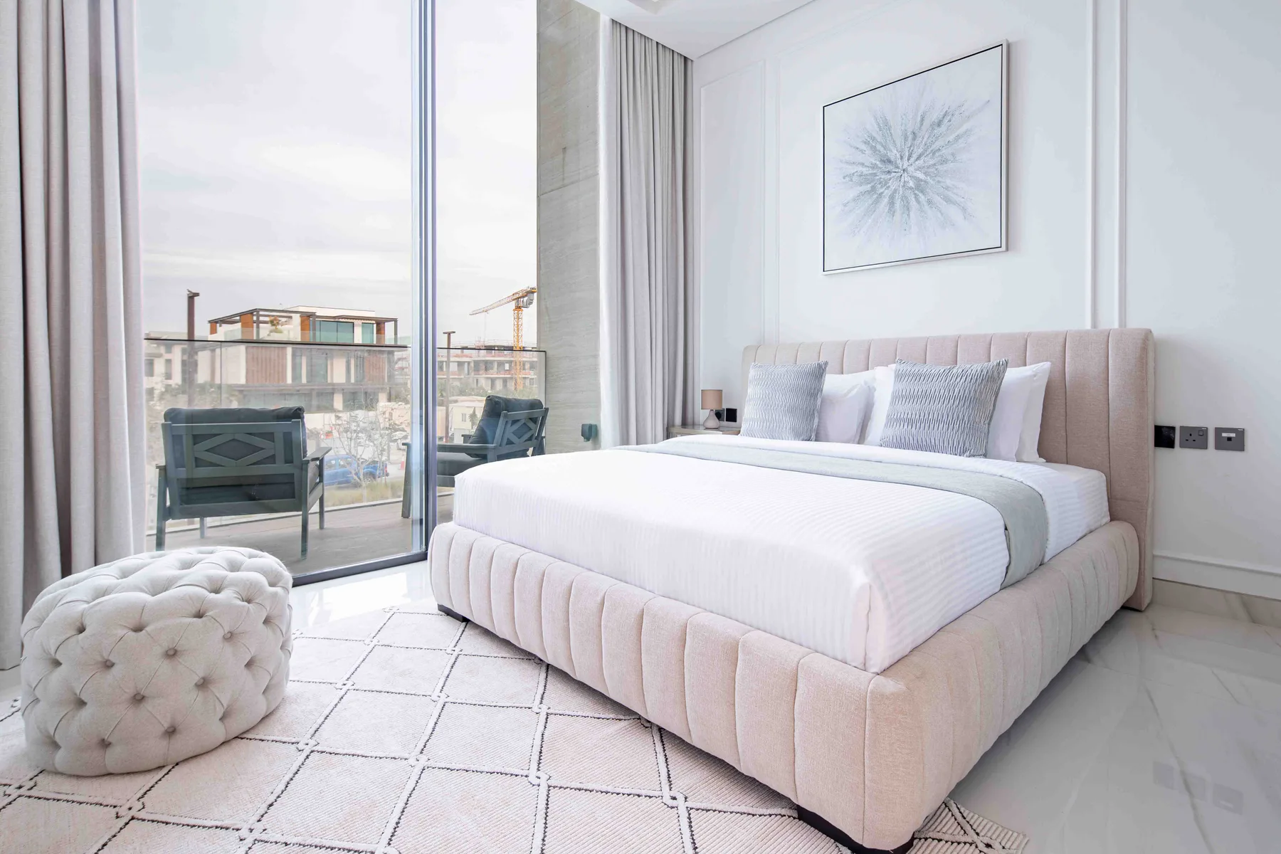 Un dormitorio luminoso con una cama grande junto a ventanales.