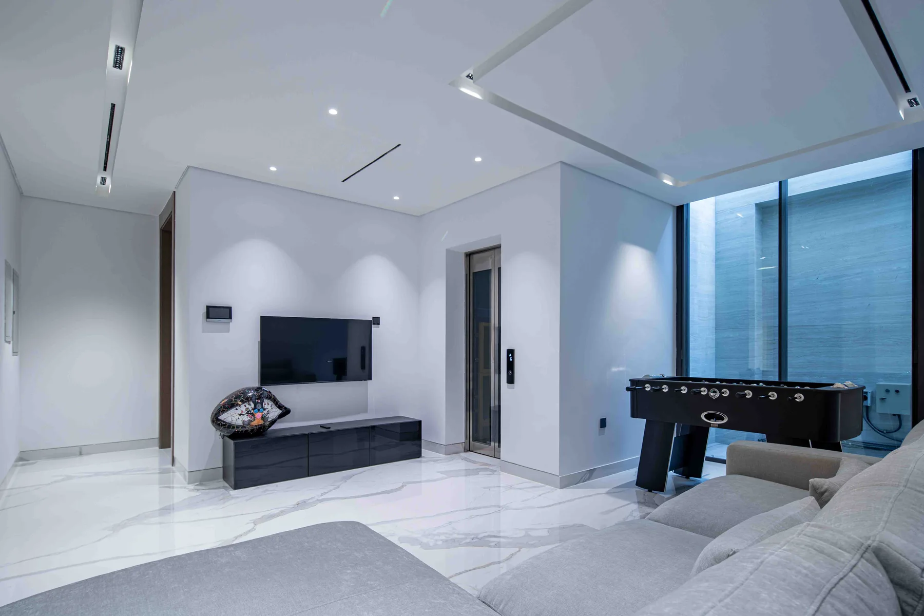 Una sala de estar moderna con televisión, asientos y una mesa de futbolín.